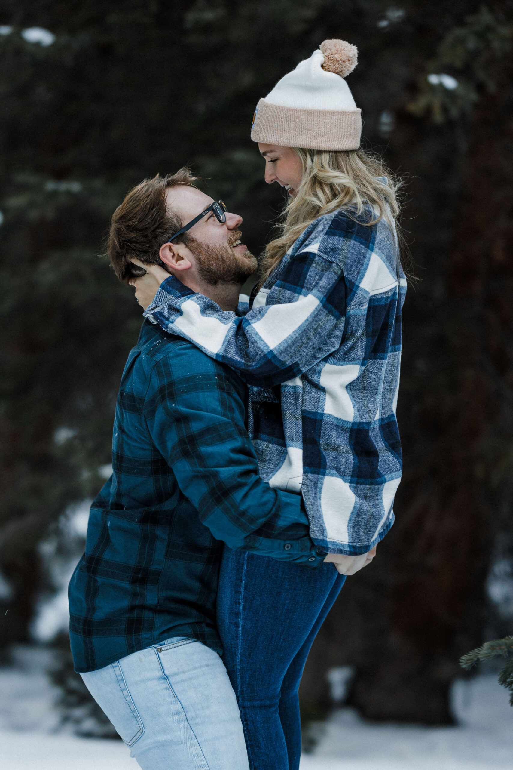 man picks up his fiance during winter engagement photo shoot.