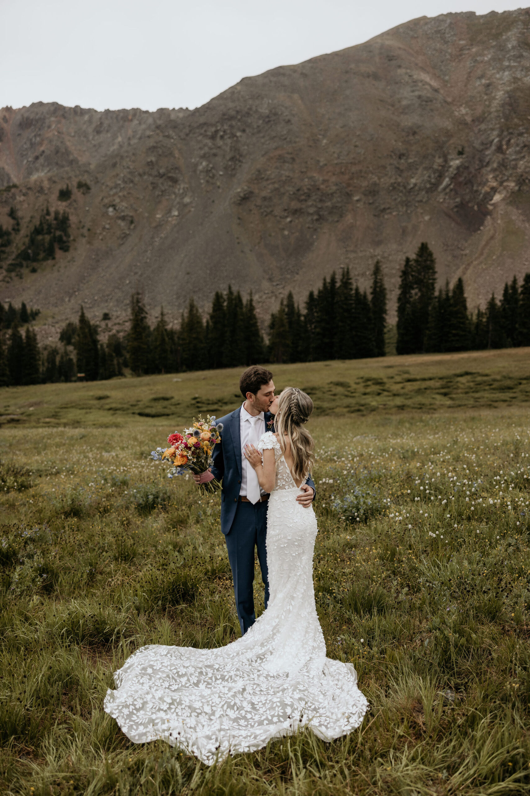 bride and groom kiss in front of the colorado mountains during their elopement.