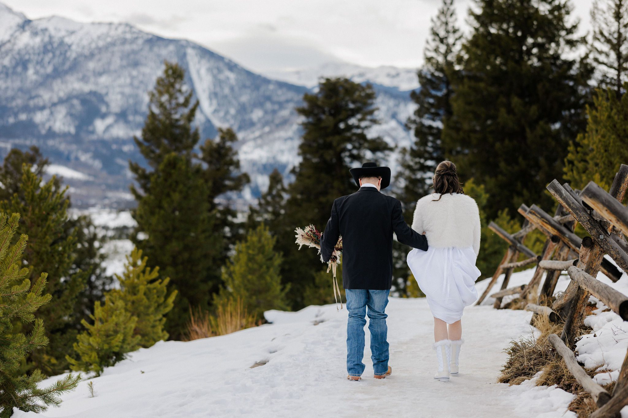 bride and groom walk along snowy trail during winter micro wedding