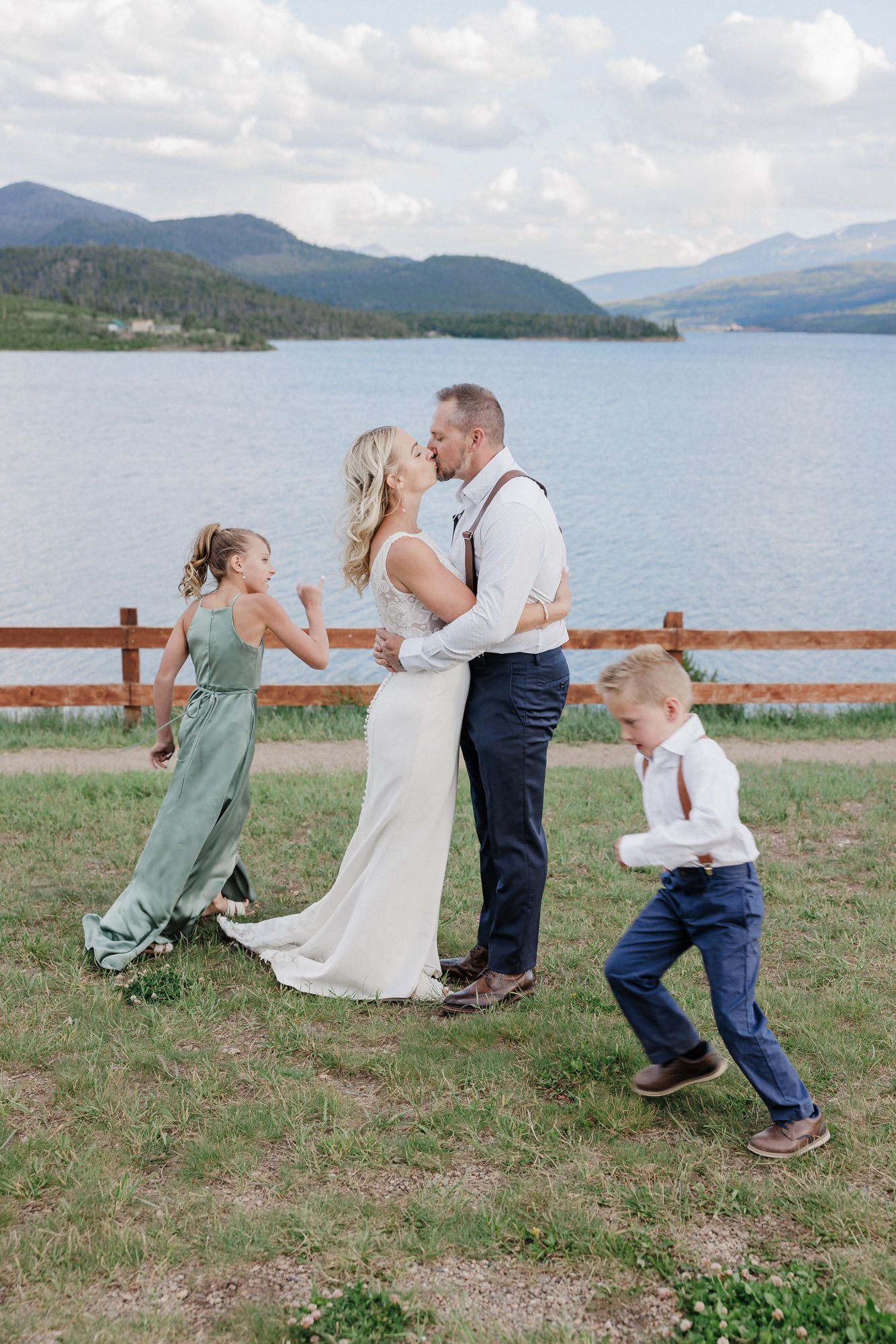 bride and groom kiss while eloping with children, and the kids run around them.