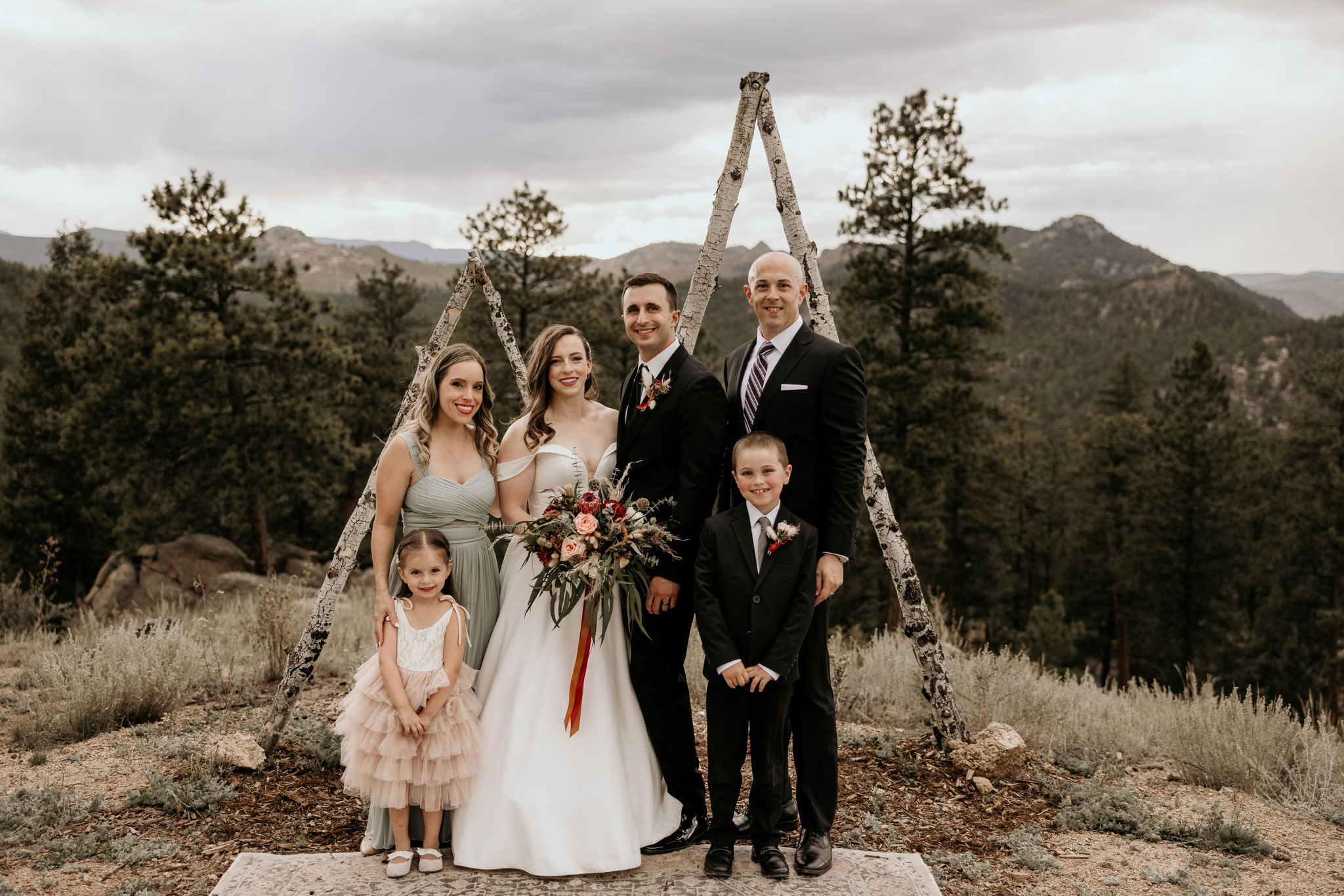 bride and groom stand with family during their mountain elopement in colorado.