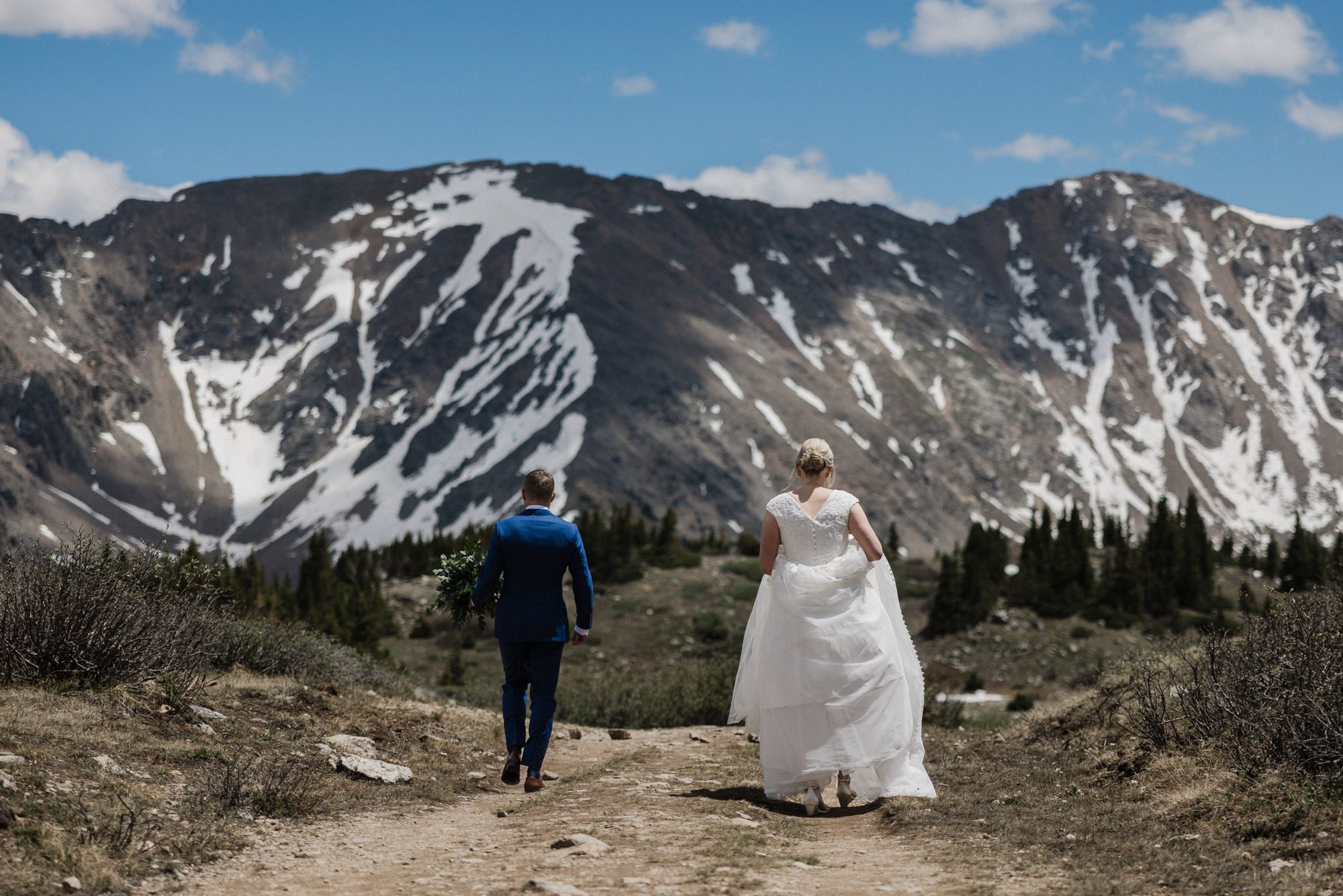 bride and groom walk up trail at loveland pass in colorado