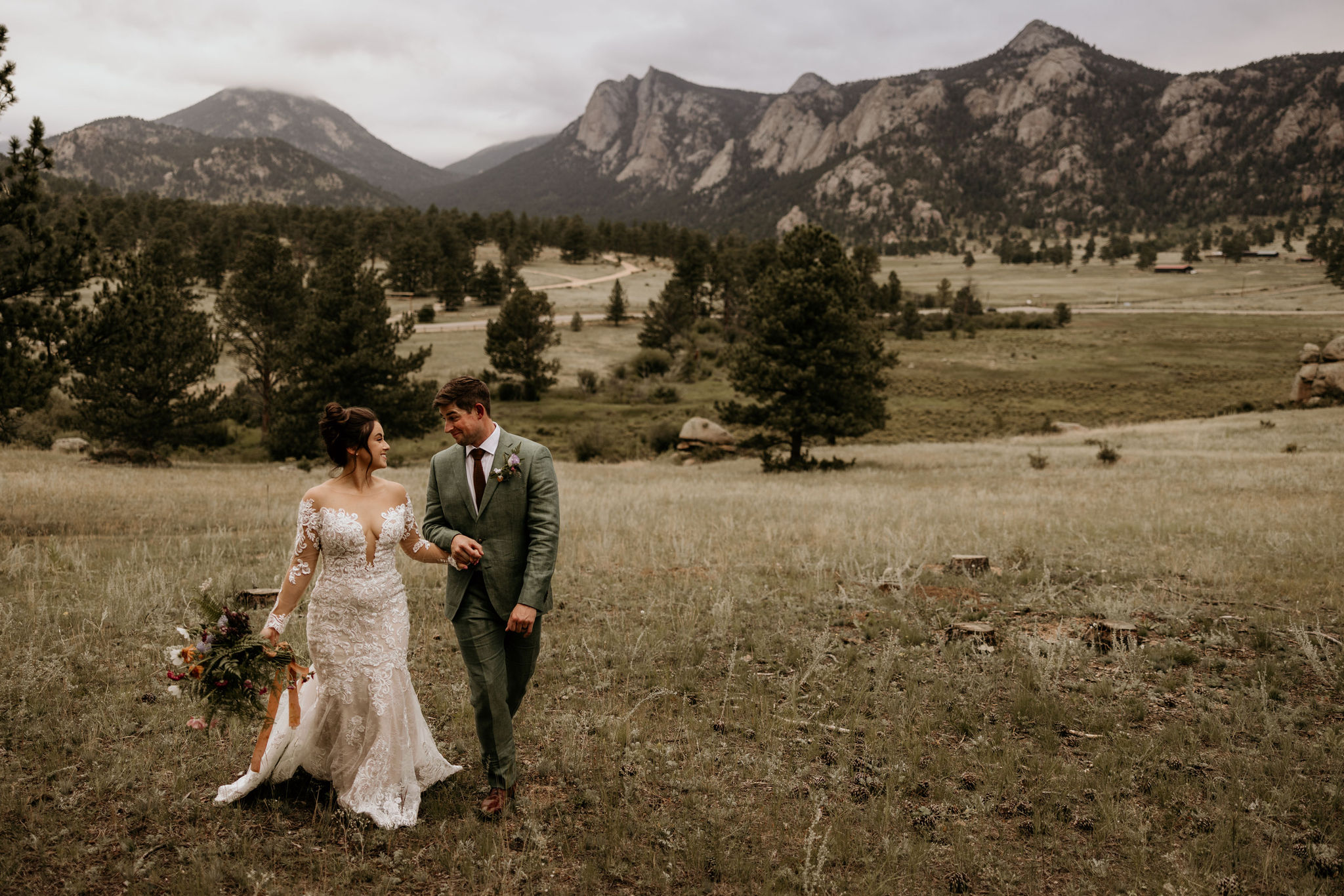 bride and groom walk through valley, surrounded by colorado mountains, during stress free elopement day.