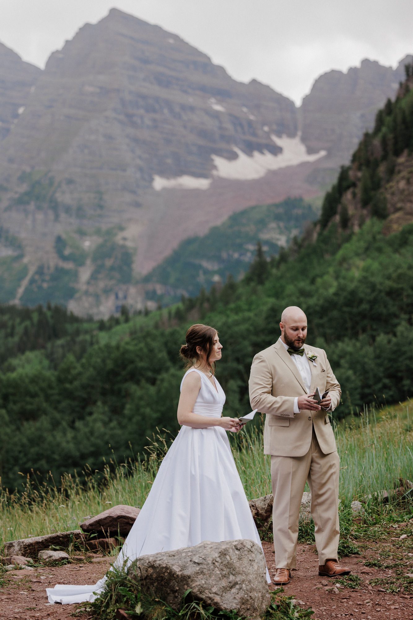 bride and groom read wedding vows during elopement at maroon bells in colorado