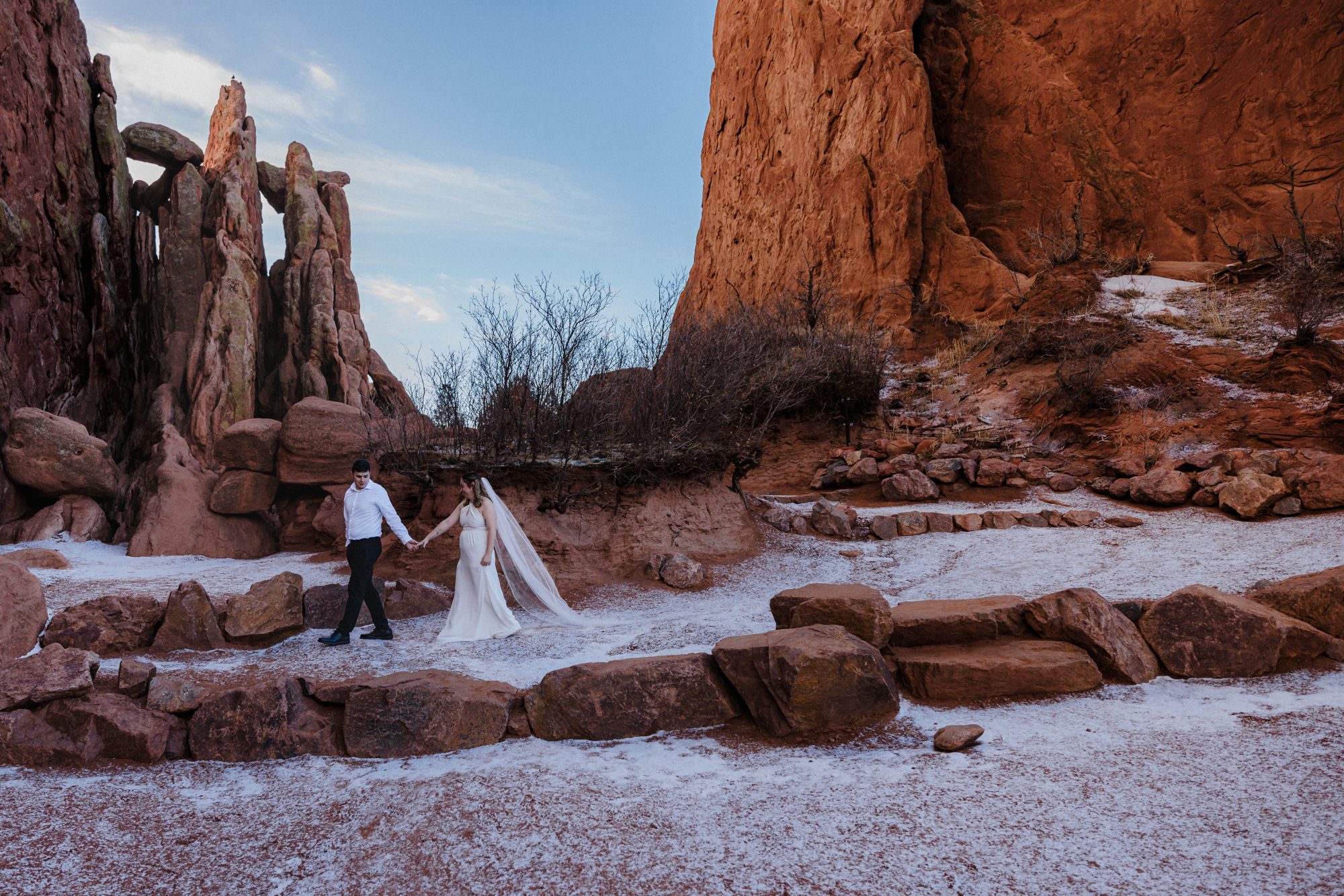 during winter elopement, bride and groom walk through the rocks at garden of the gods 