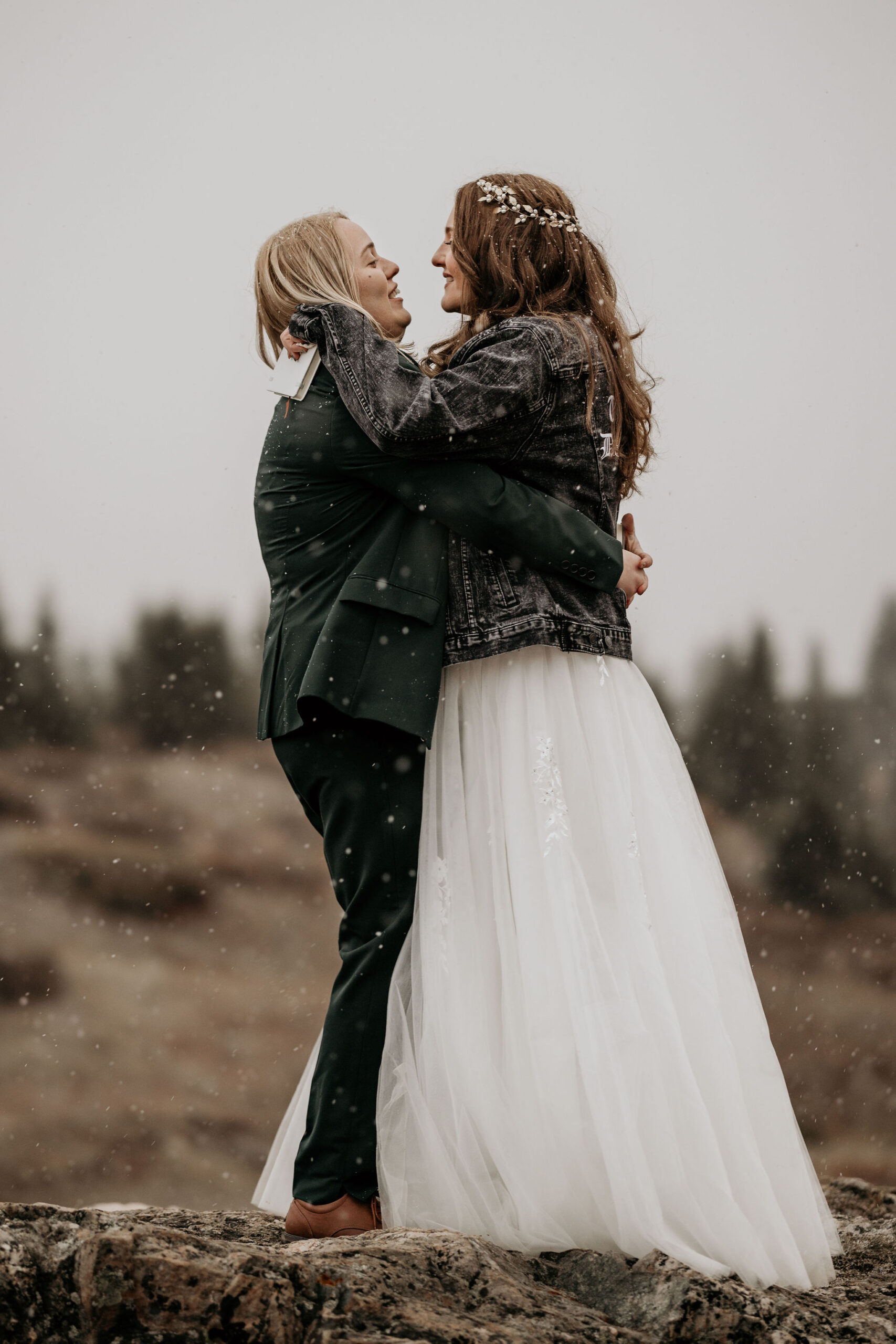 Two brides hug in the snow after canceling their wedding to elope.