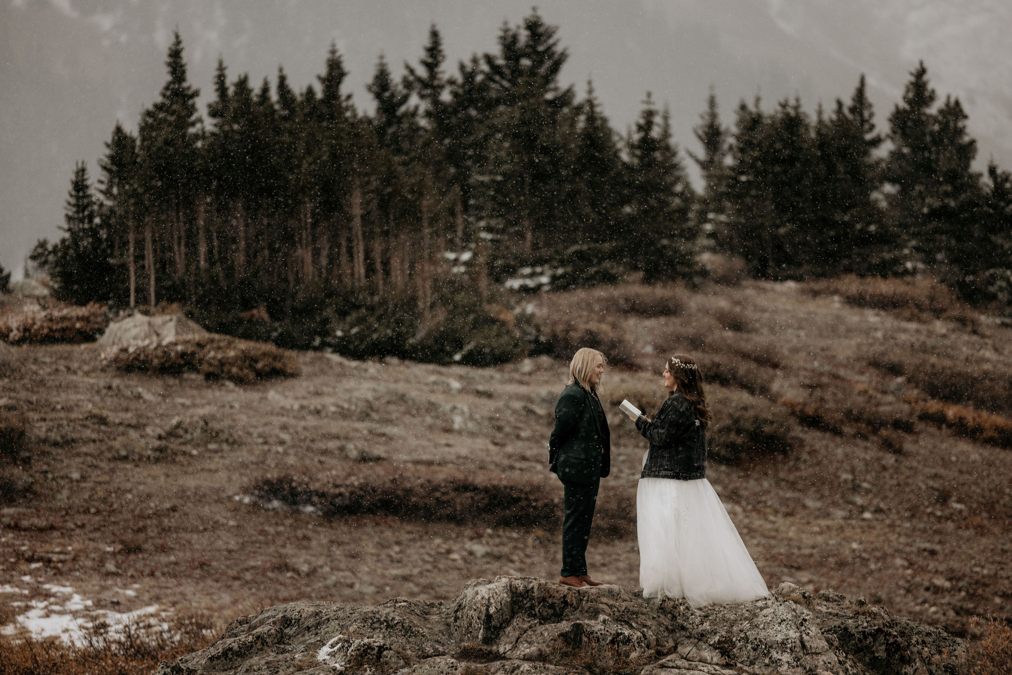 LGBTQ+ couples read wedding vows outside on rock in front of the colorado mountains.