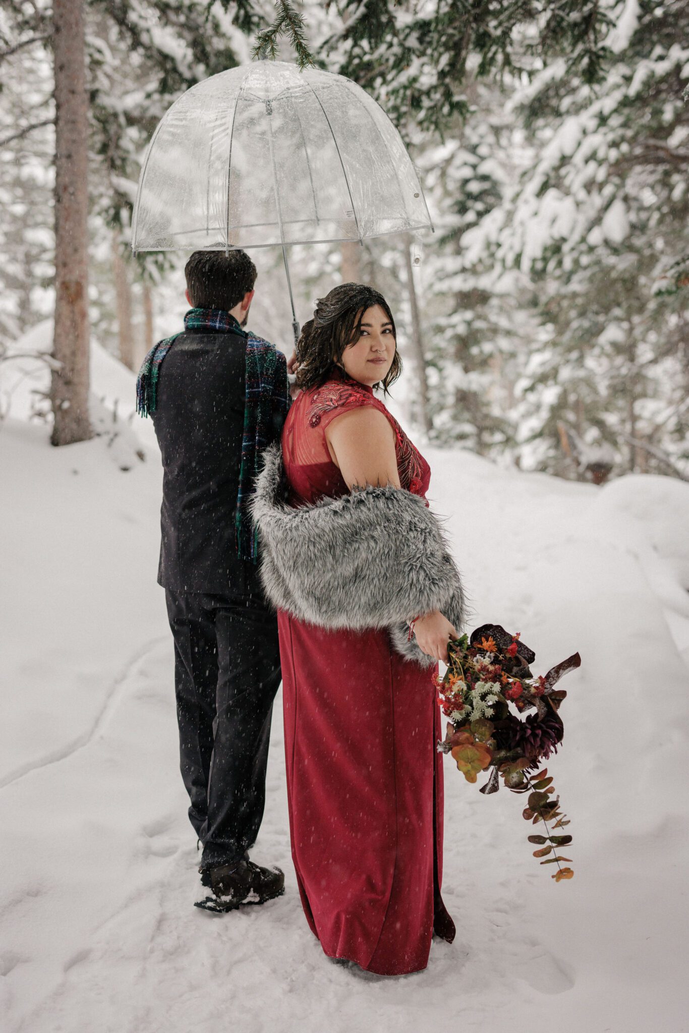 bride and groom walk along snowy trail at rmnp