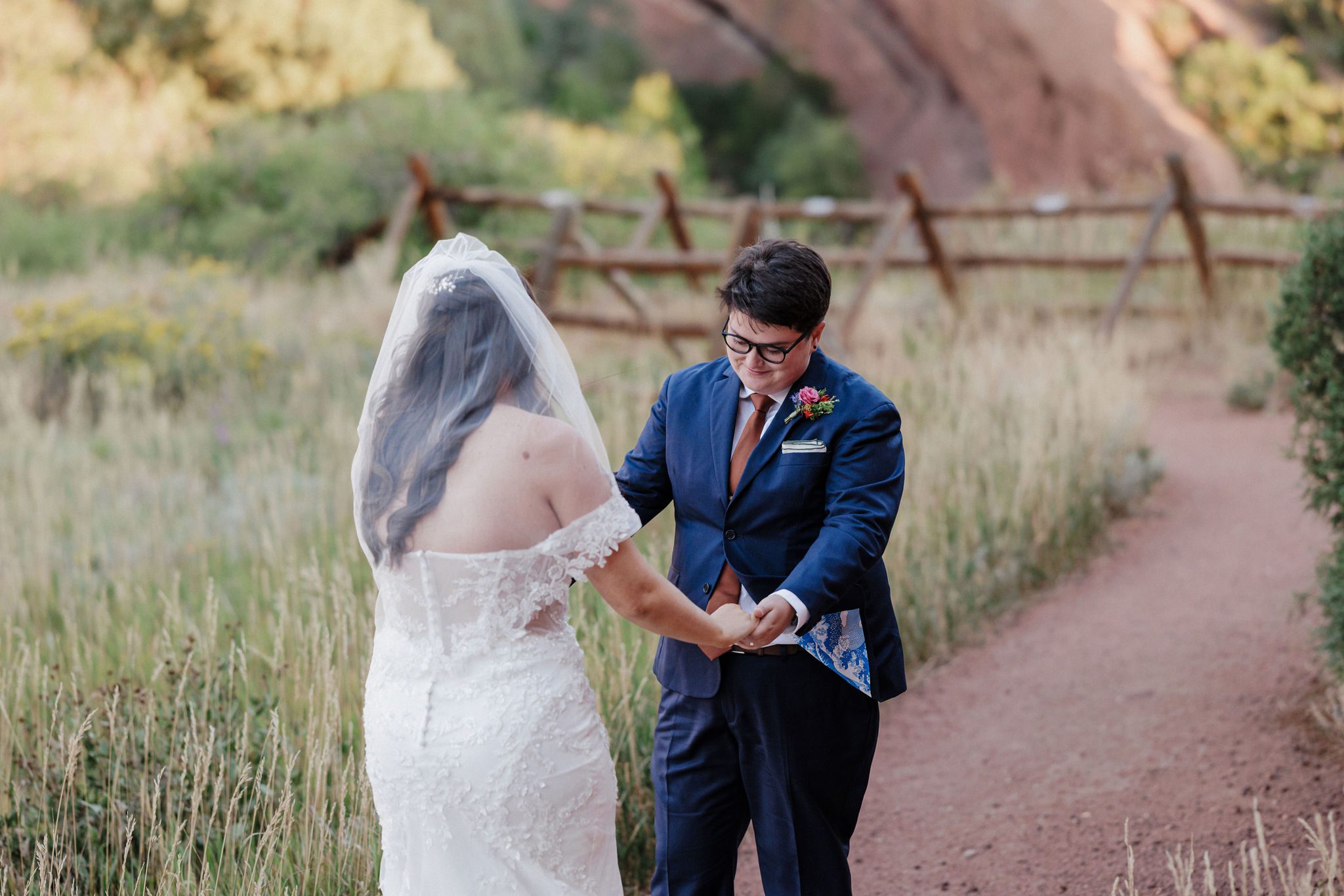 two brides hold hands and smile as they see each other for their wedding day first look