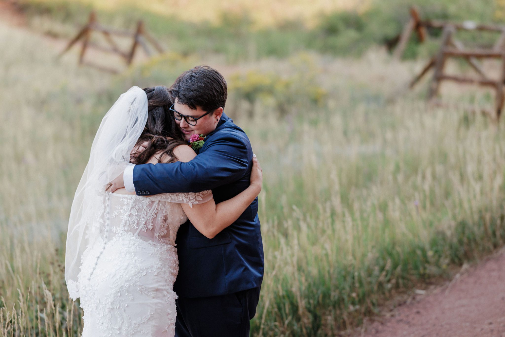 two brides hug each other during their wedding day first look at red rocks park in colorado
