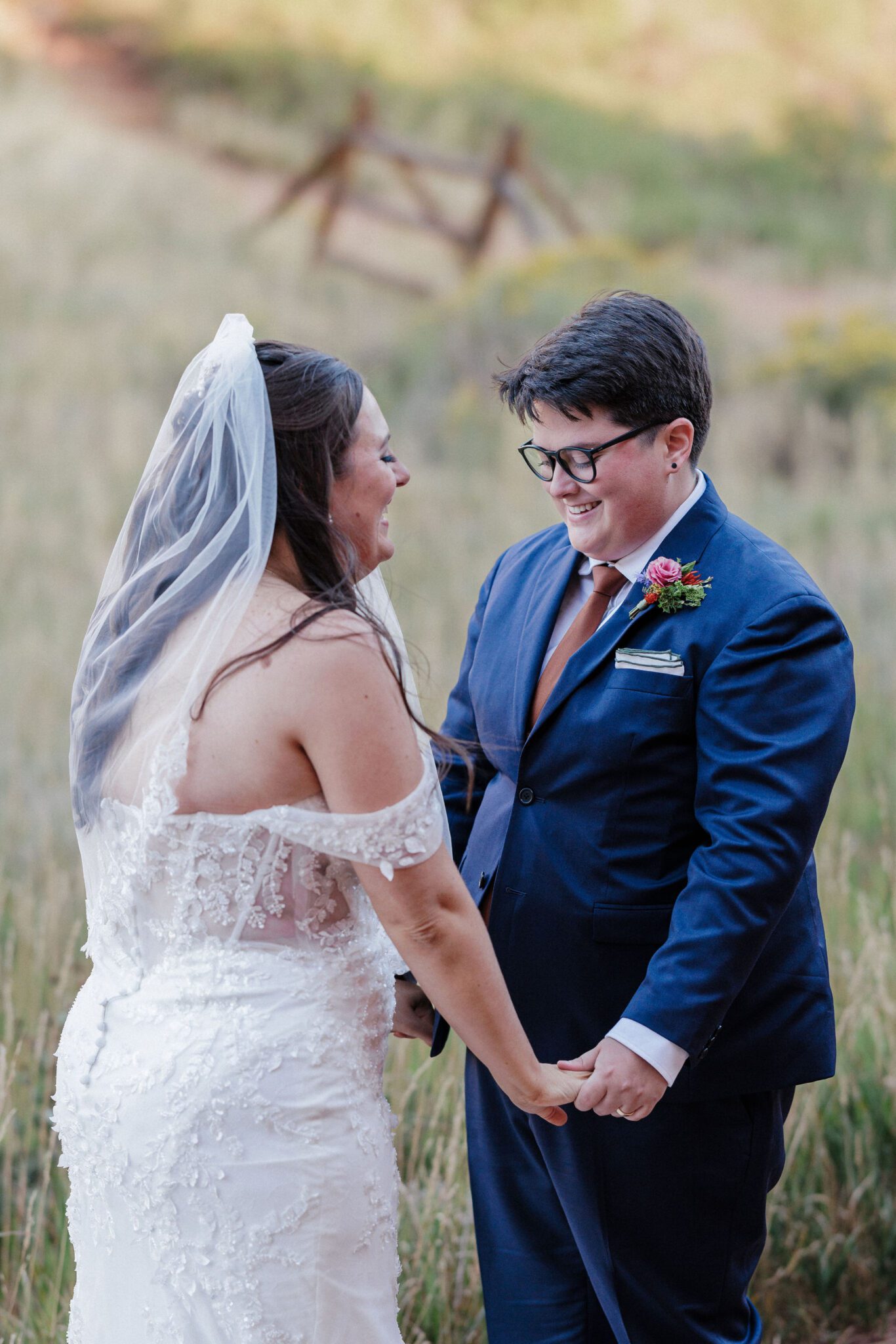 two brides hold hands and giggle after doing their first look idea for their wedding in red rocks park