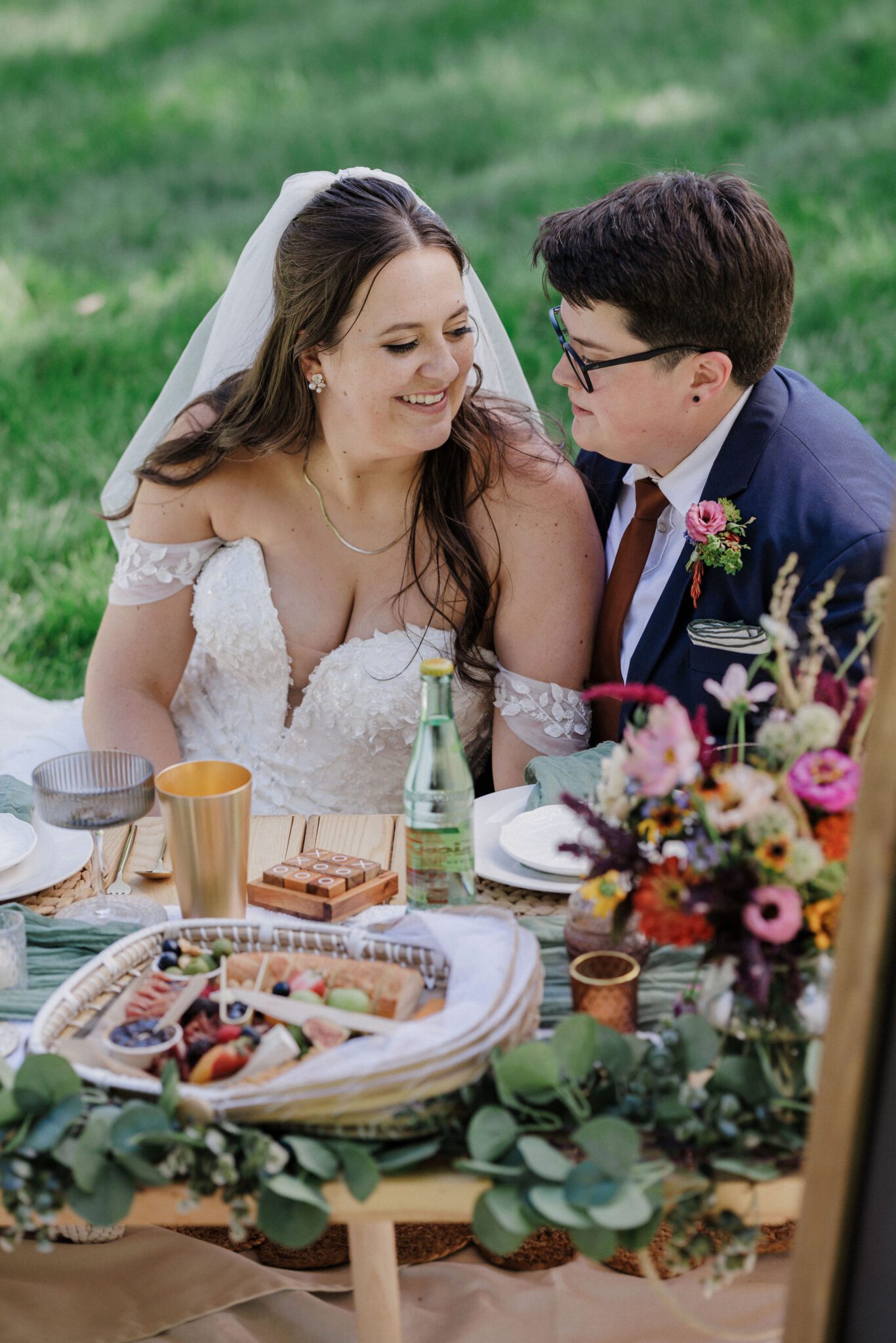 two brides smile at each other at their luxury picnic - they got a luxury colorado elopement package