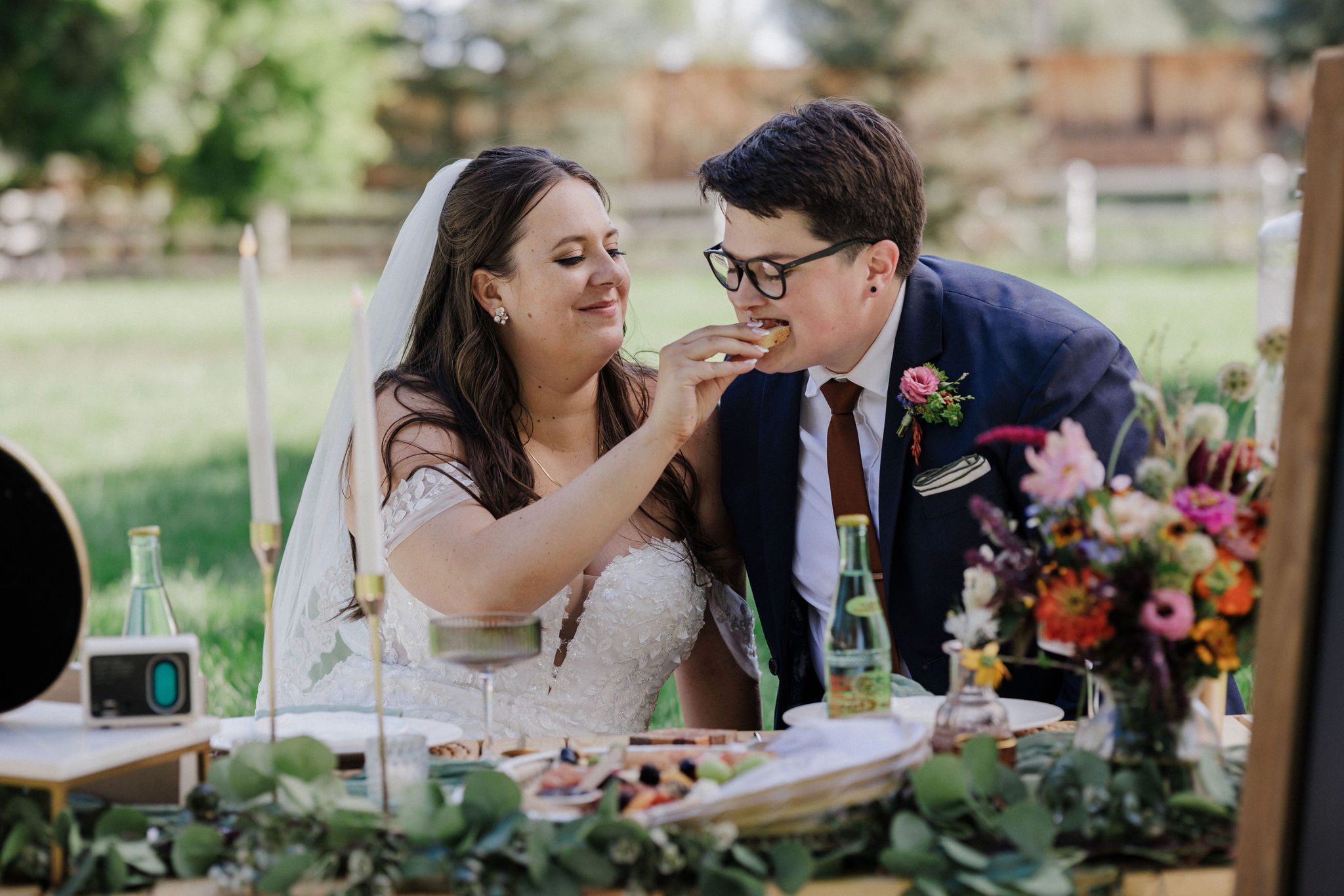 bride feeds the other bride a snack from their luxury wedding picnic