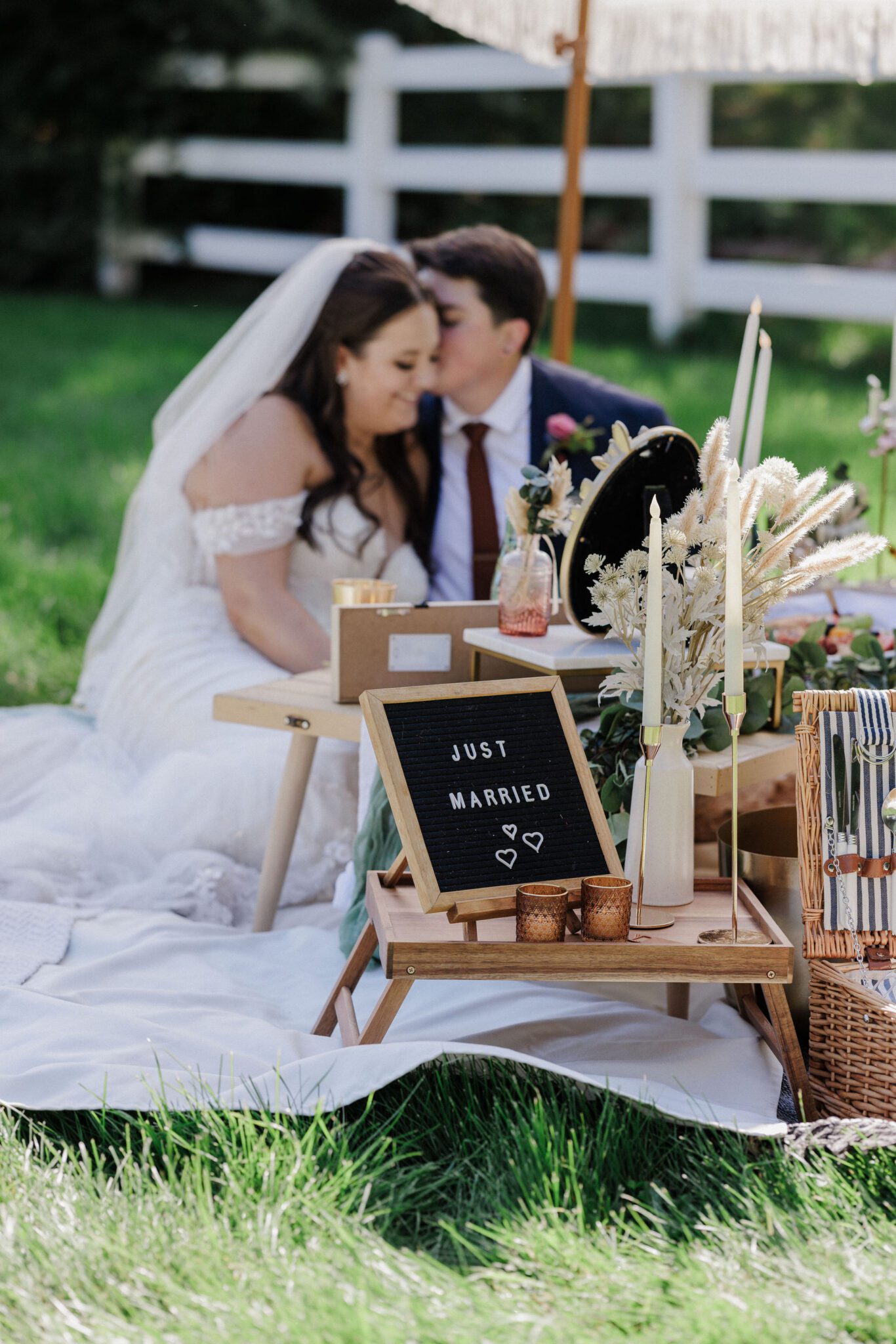 bride whispers to the other bride, blurred in the background, with a 'just married' sign in the foreground for their colorado elopement package choice