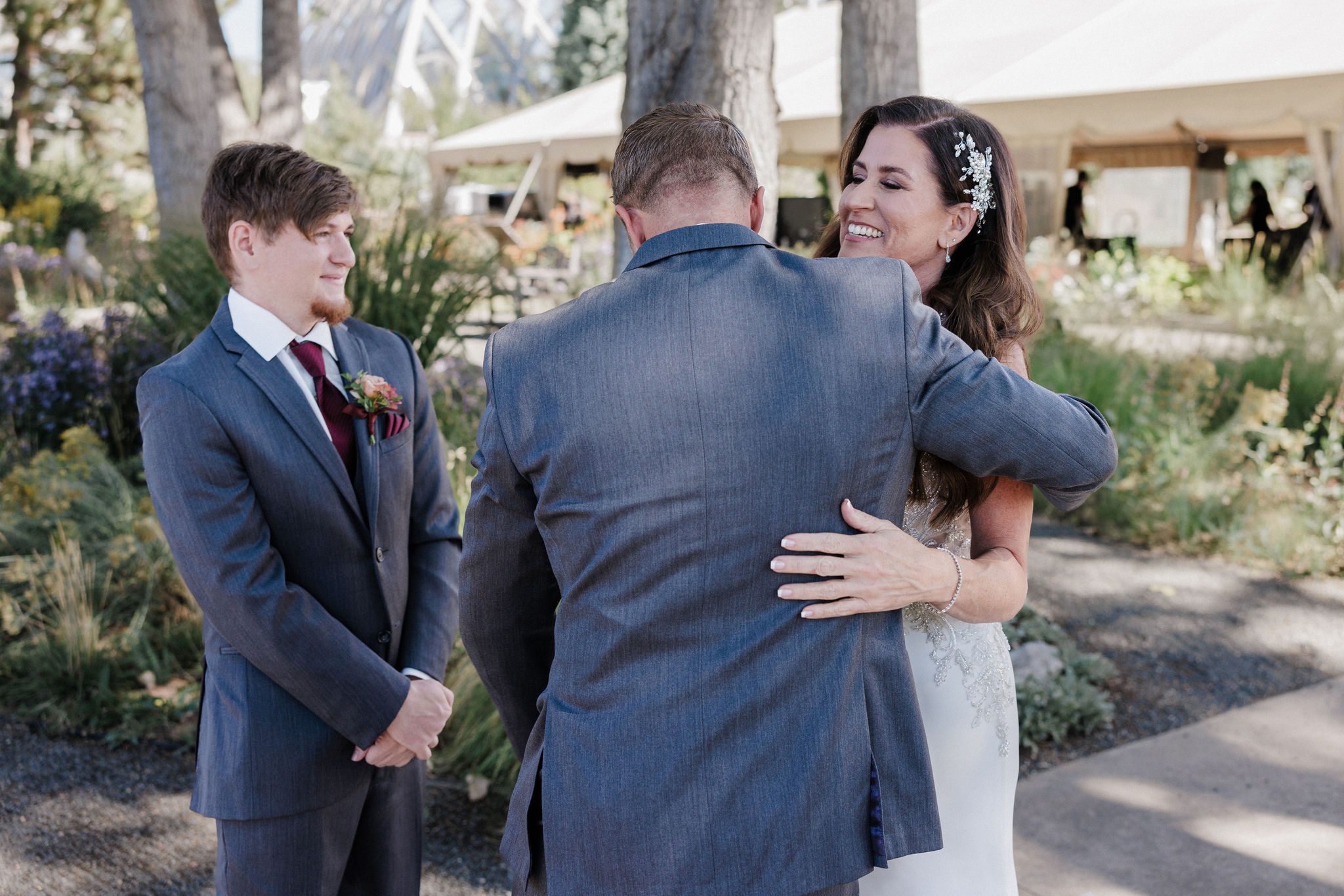 bride hugs one of her sons during a wedding day first look with her family