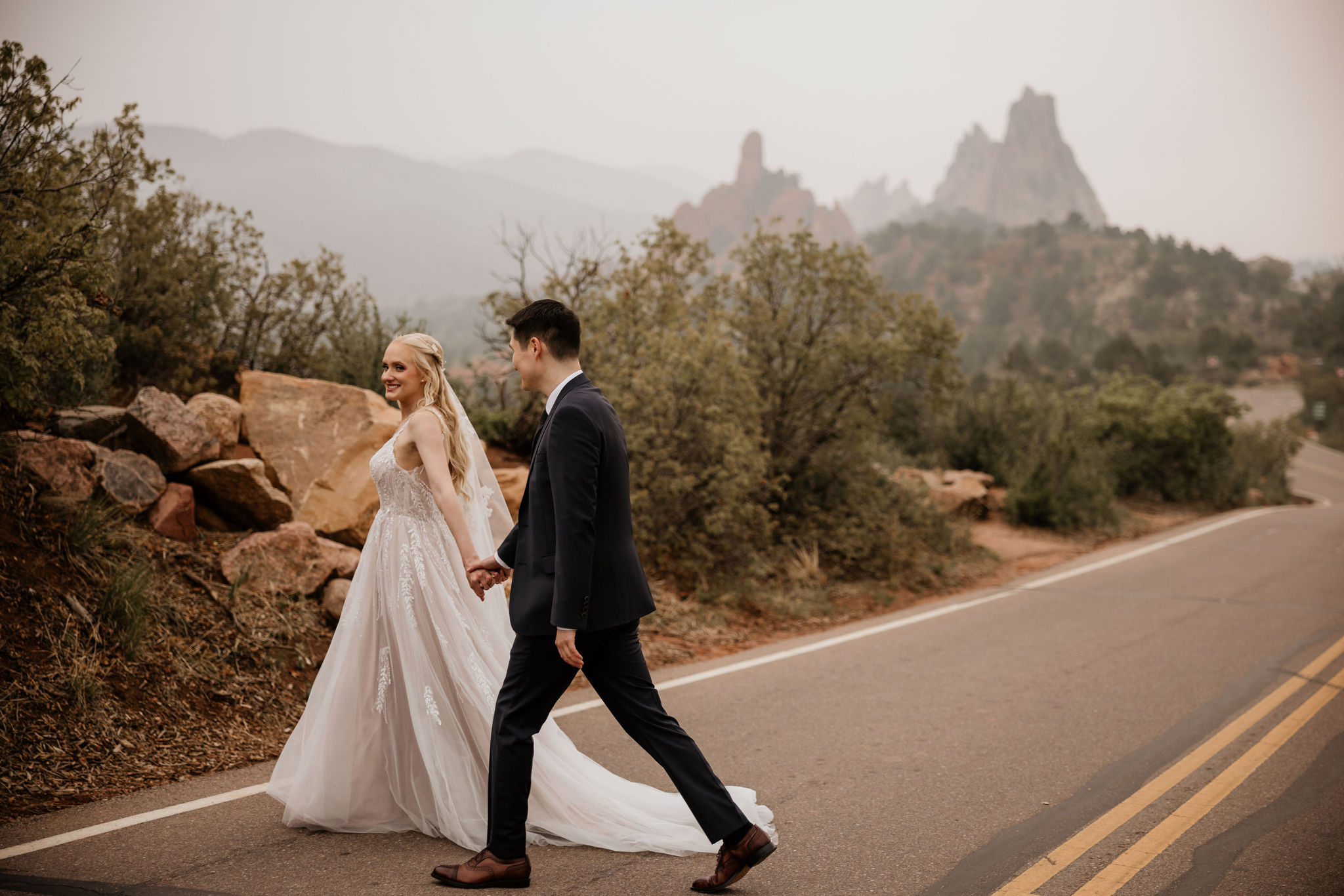 bride and groom walk across the road at garden of the gods during luxury elopement.