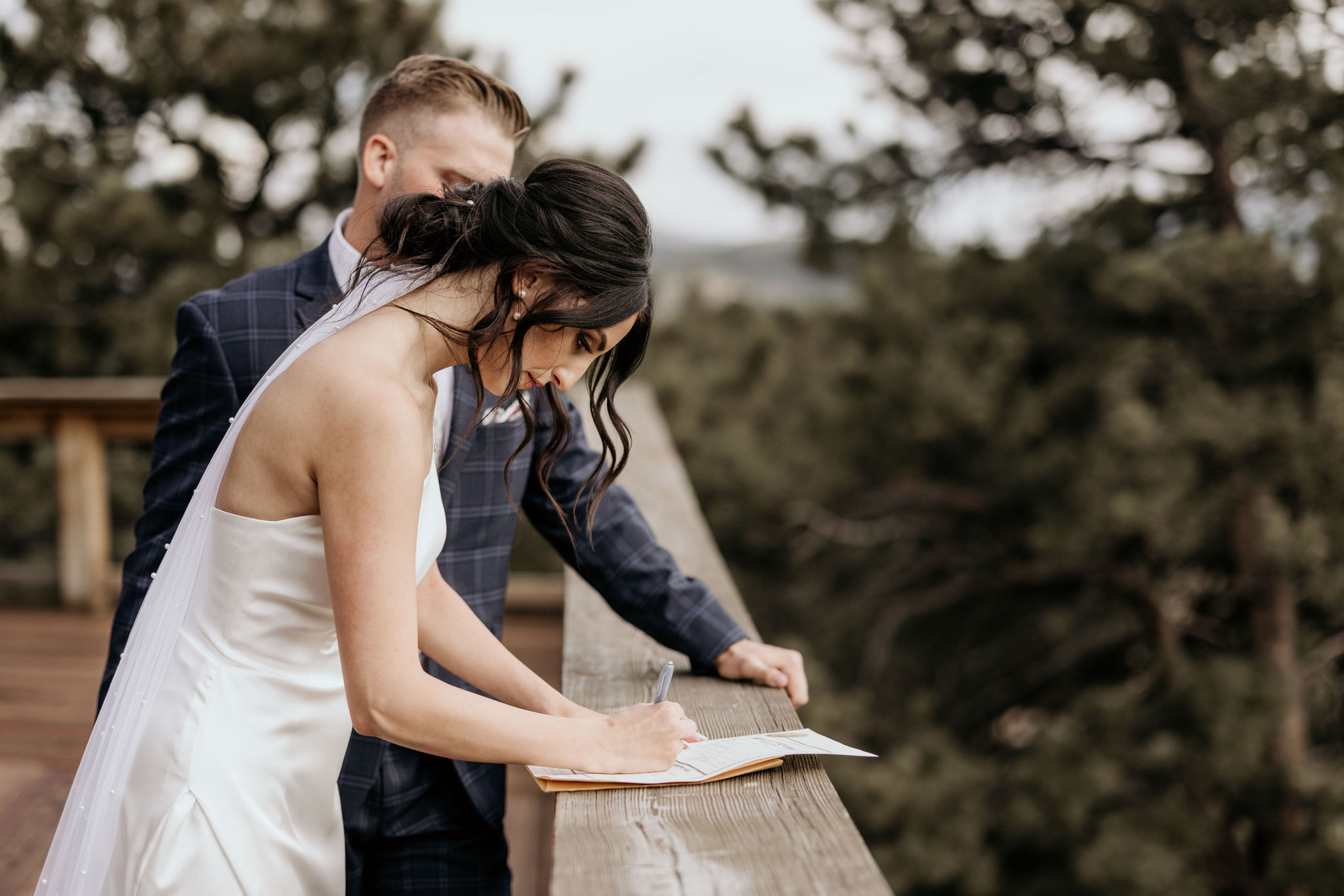 bride and groom sign marriage certificate during colorado micro wedding in the mountains
