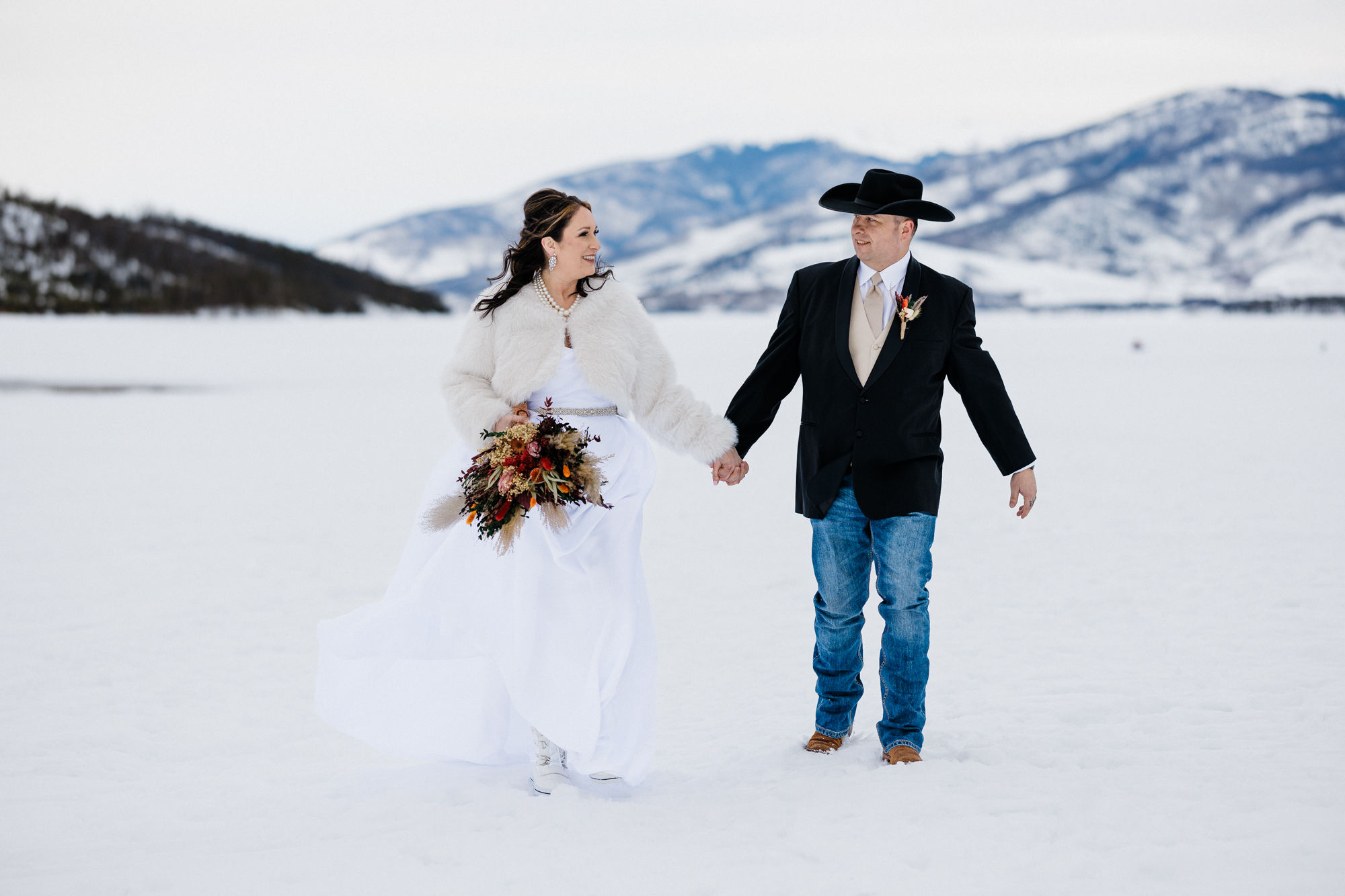 bride and groom hold hands and hike through snow during their second wedding elopement.