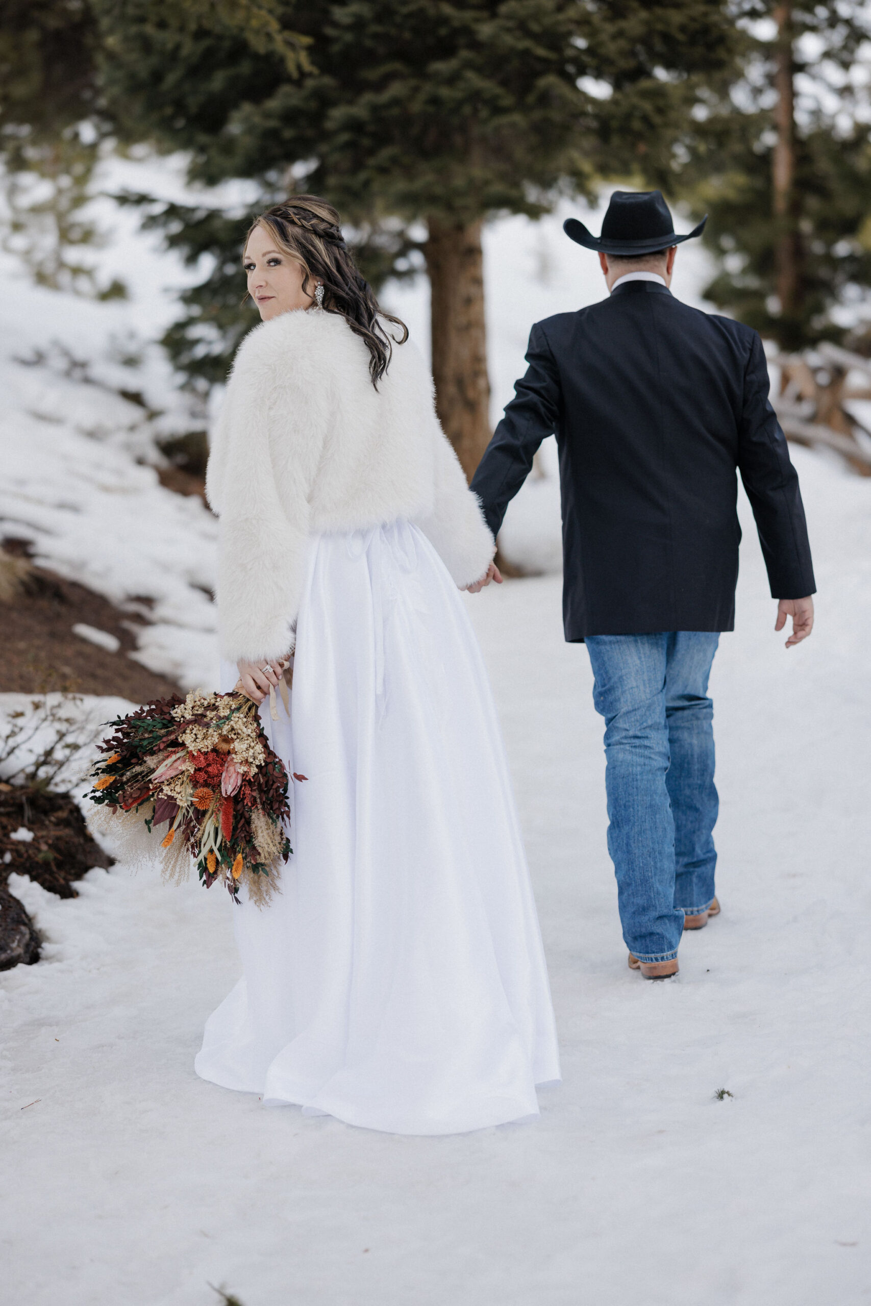 bride and groom hold hands and walk along trail during sapphire point elopement