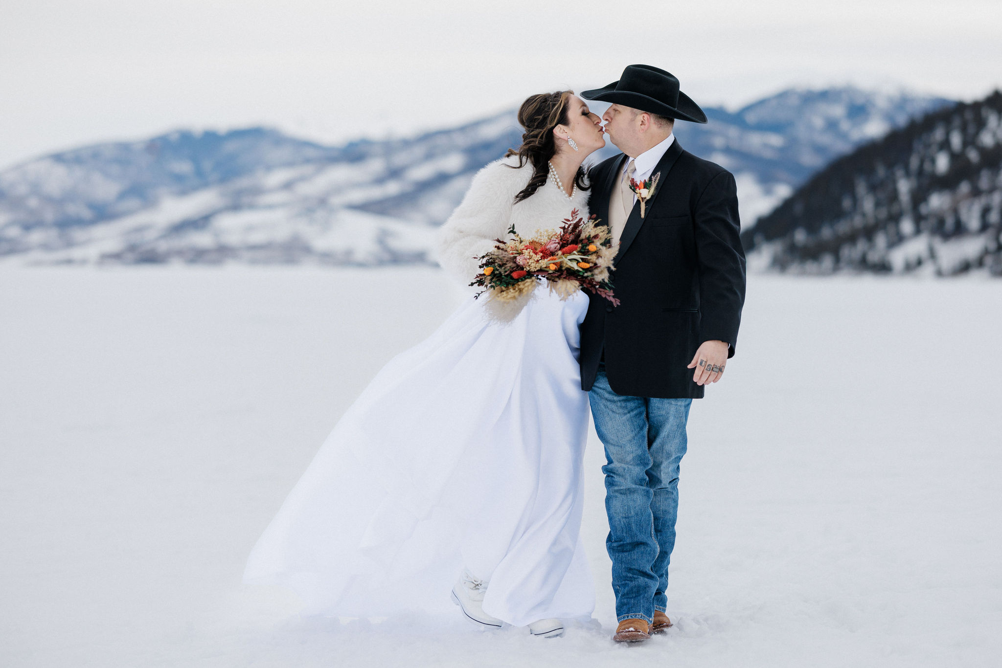bride and groom kiss while walking on a trail in the colorado mountains