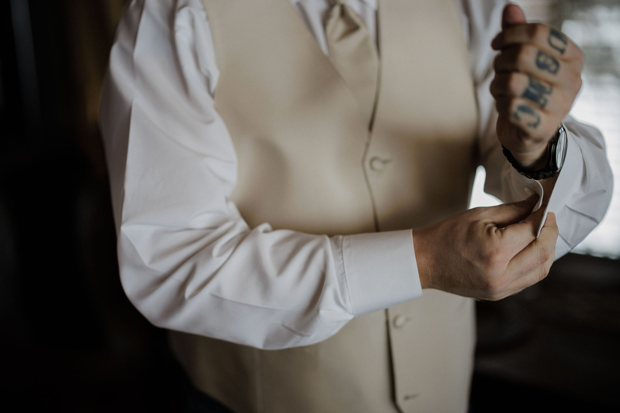 groom puts cufflinks on for wedding day
