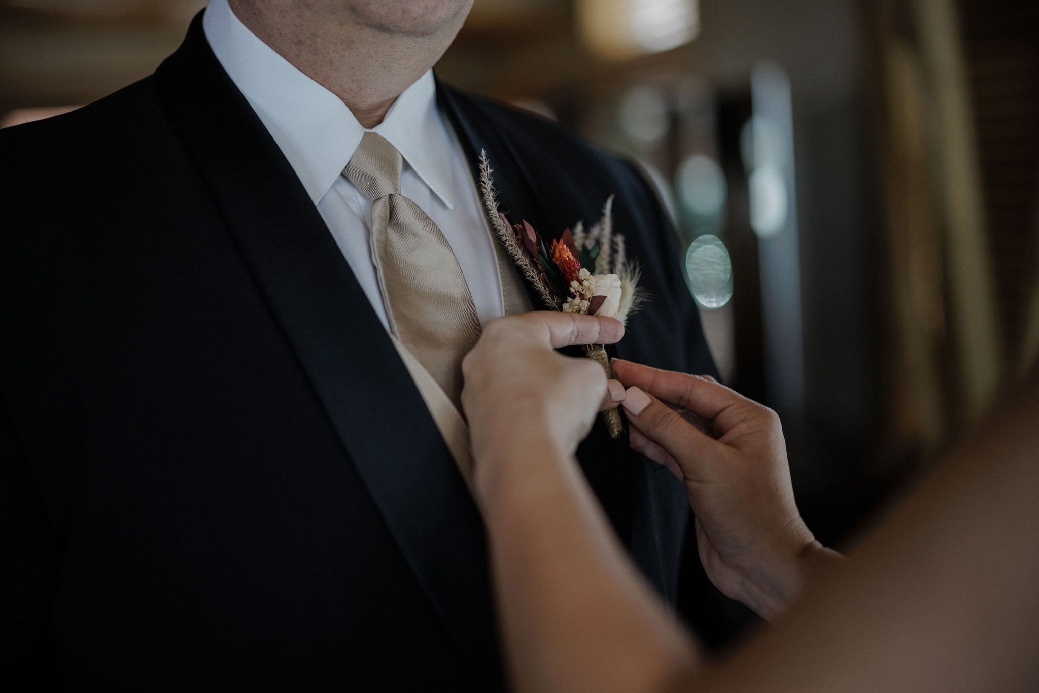 bride puts bouttoniere on groom during colorado elopement day