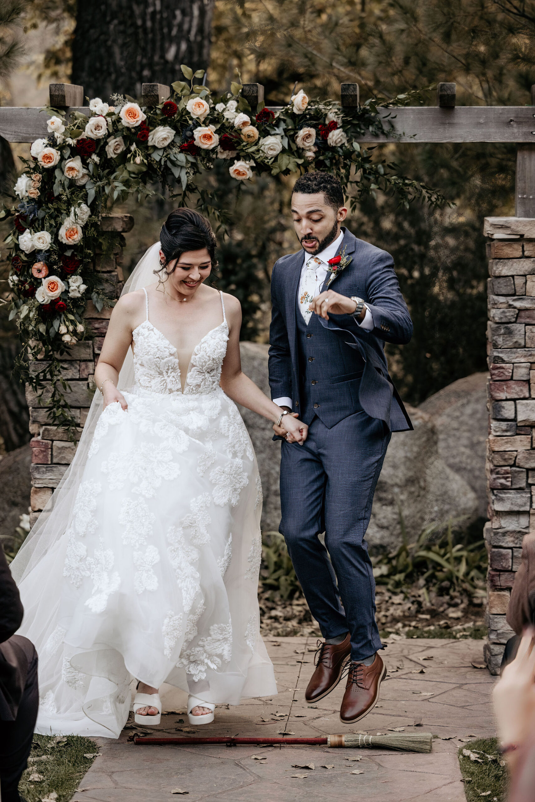 bride and groom jump over broom during colorado mountain micro wedding.