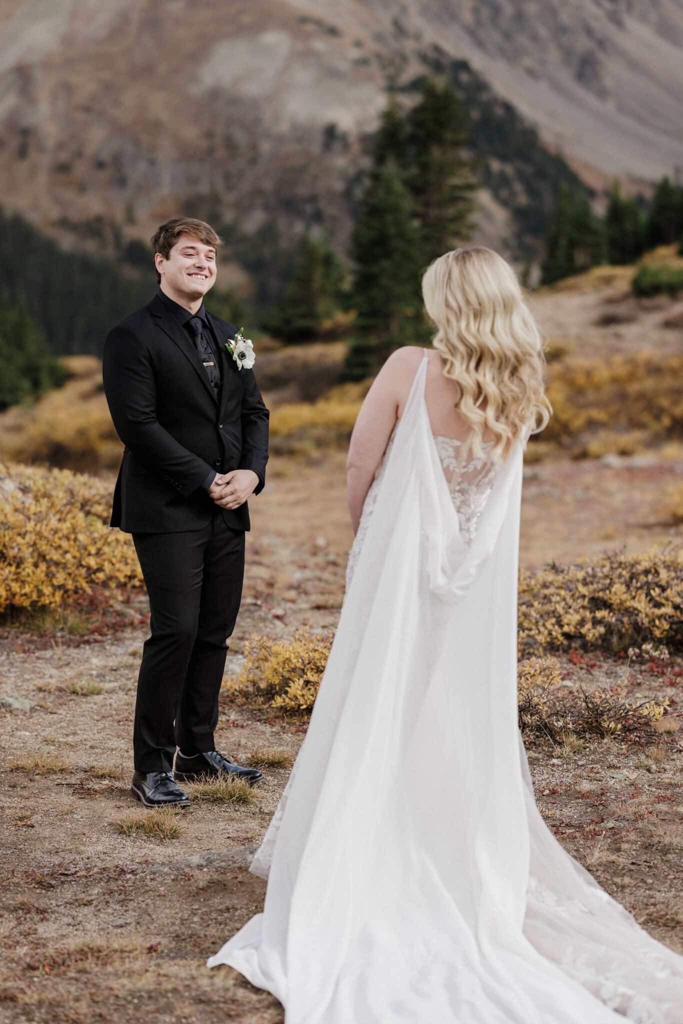 groom is facing the bride during their wedding day first look in the mountains