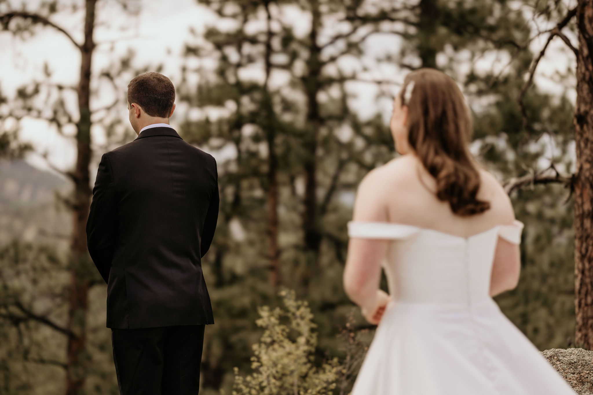 bride and groom stand in forest during wedding day first look