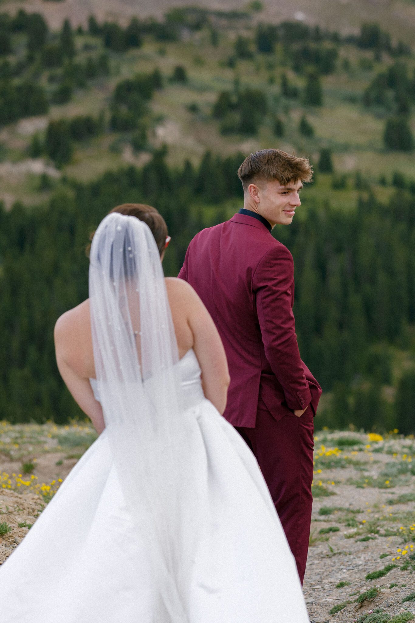 bride stands behind groom that is turning towards her as a first look idea for their wedding. they are on a train in the colorado mountains