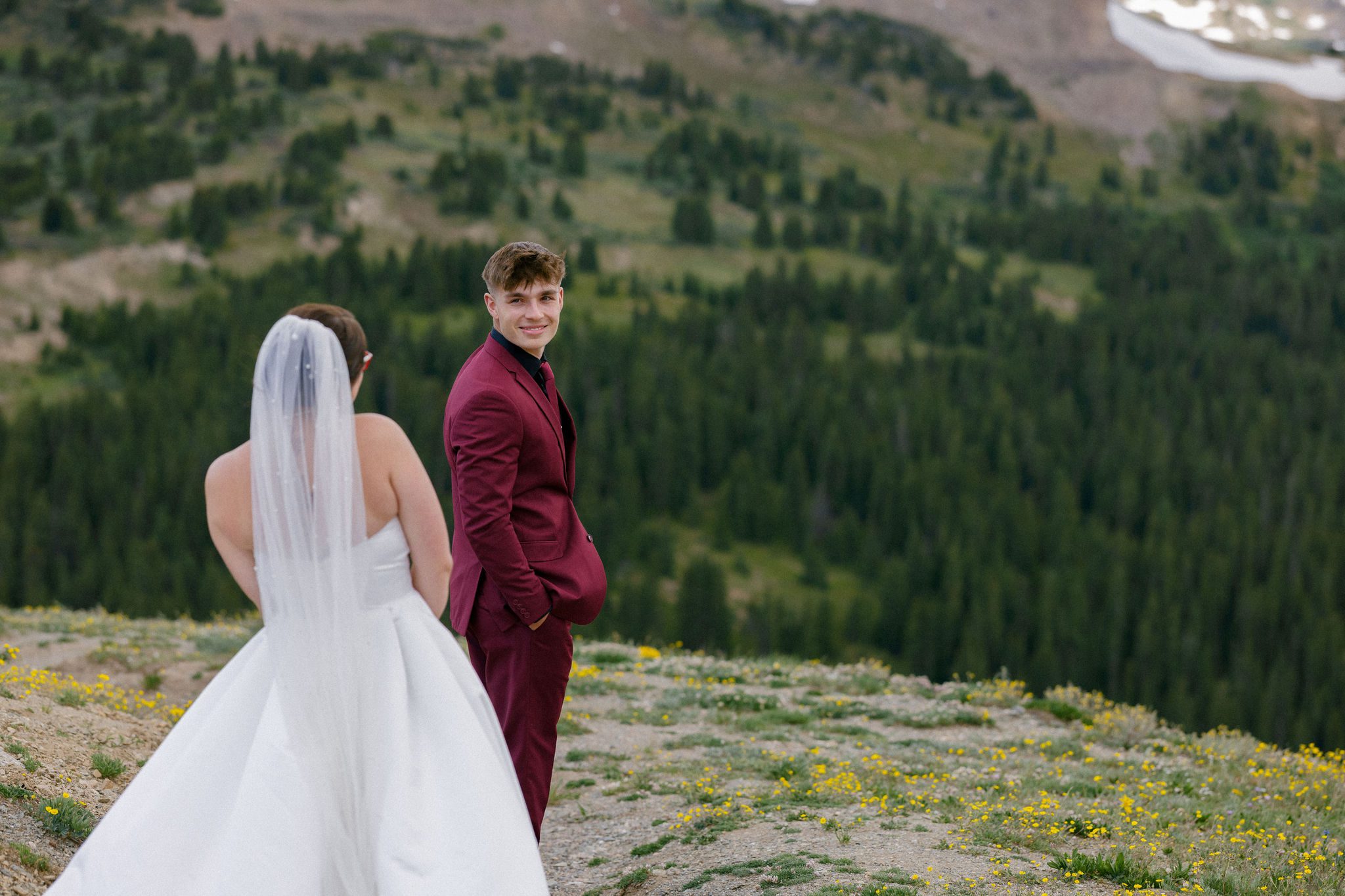 bride stands behind groom that is turning towards her and smiling as a first look idea for their wedding. they are on a train in the colorado mountains