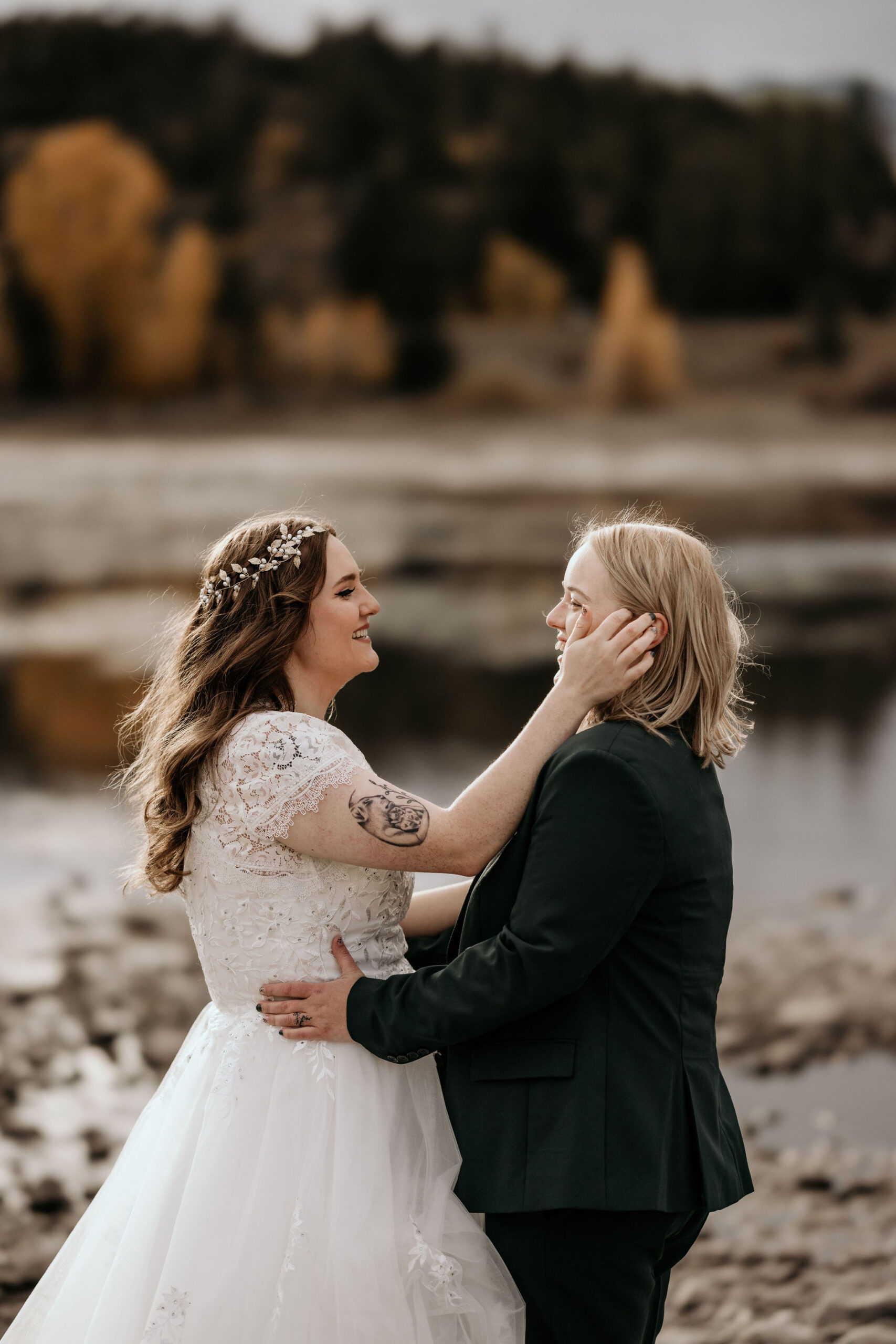 LGBTQ+ couple smiles at each other during colorado wedding day in the mountains