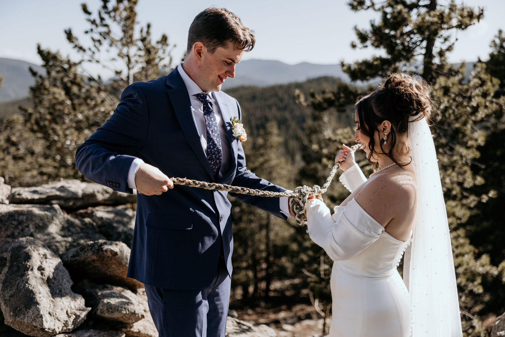 bride and groom tie hands together during self-officiating colorado wedding.