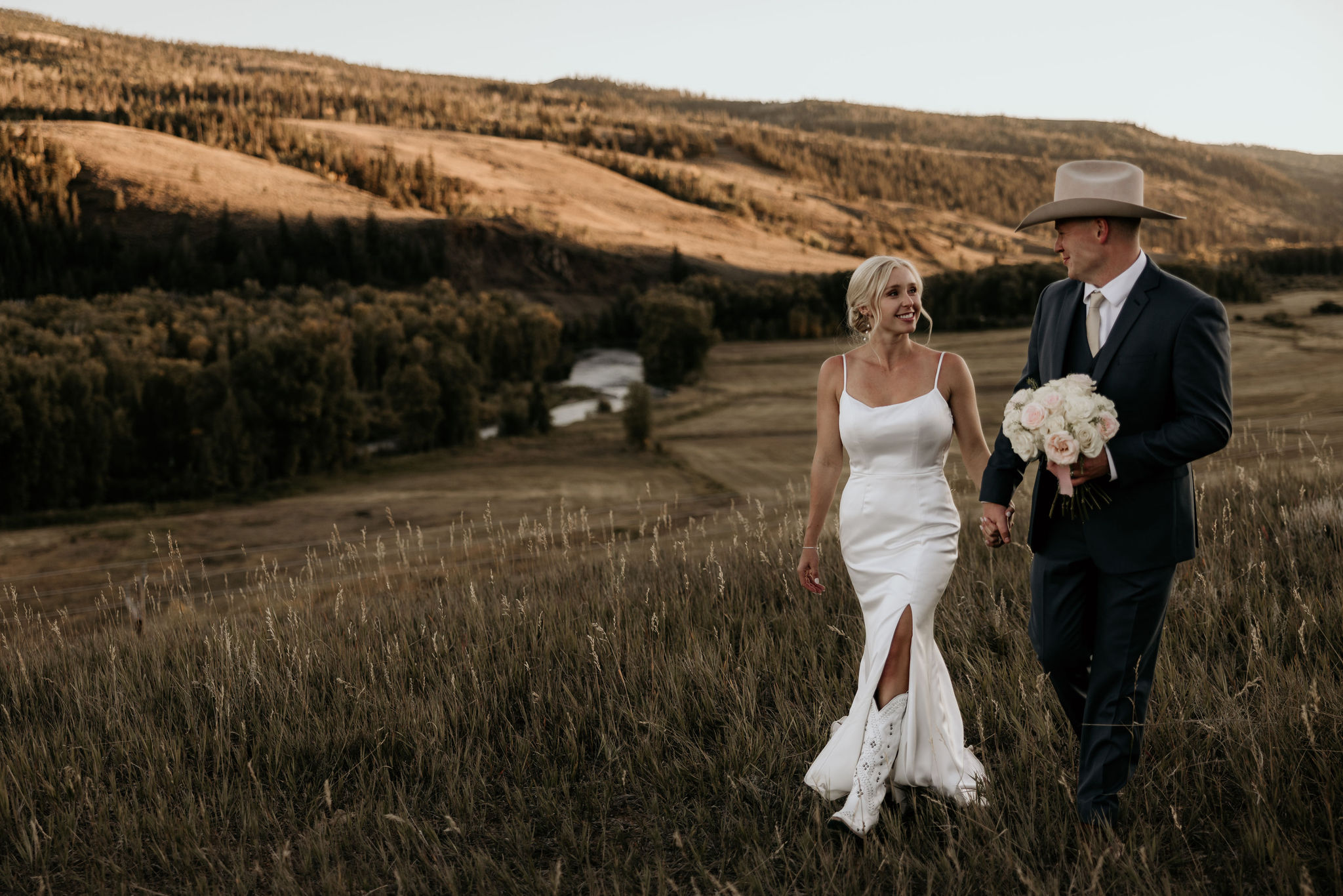 bride and groom walk through field and smile during adventure elopement