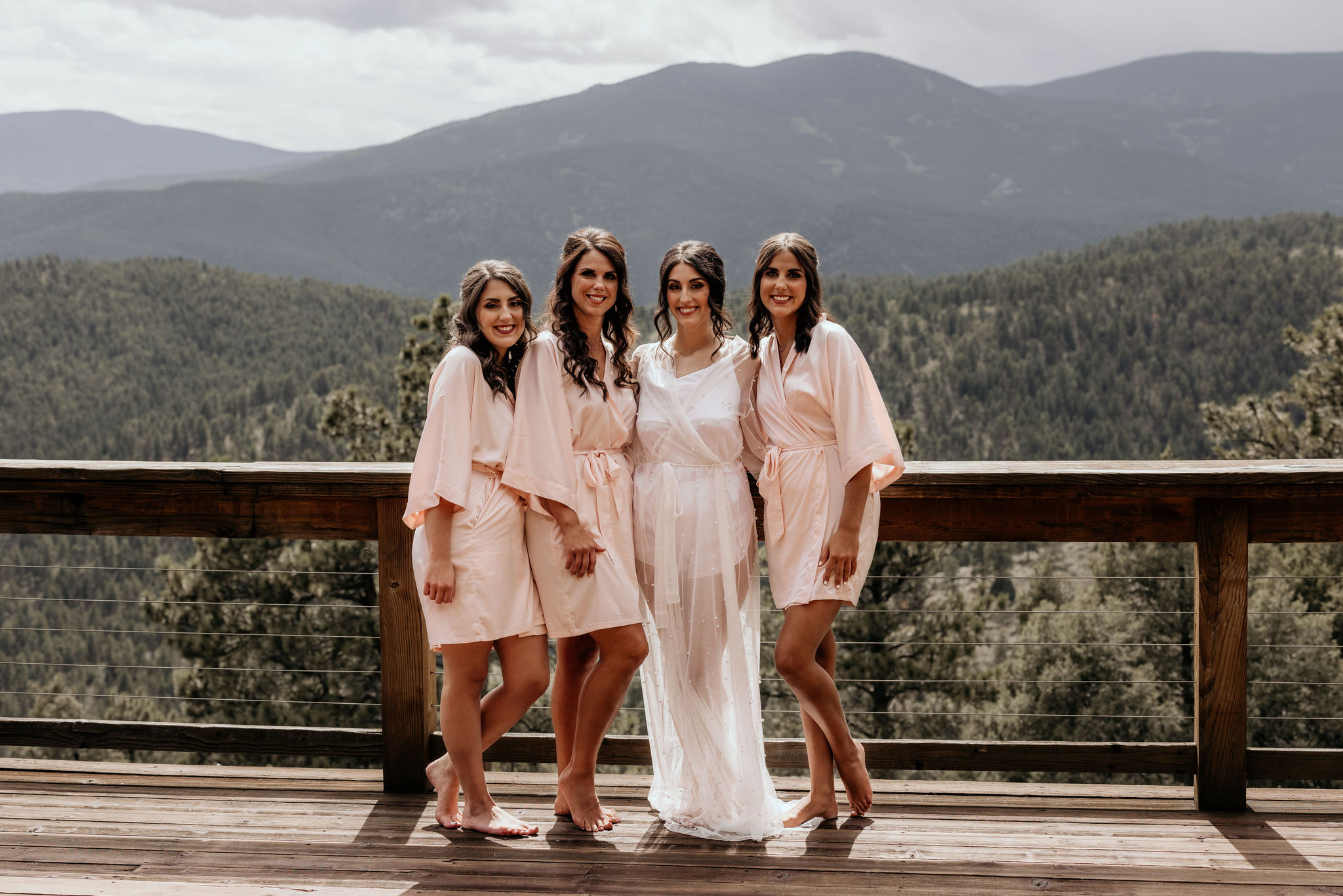 bride and bridesmaids stand on deck of airbnb during colorado micro wedding