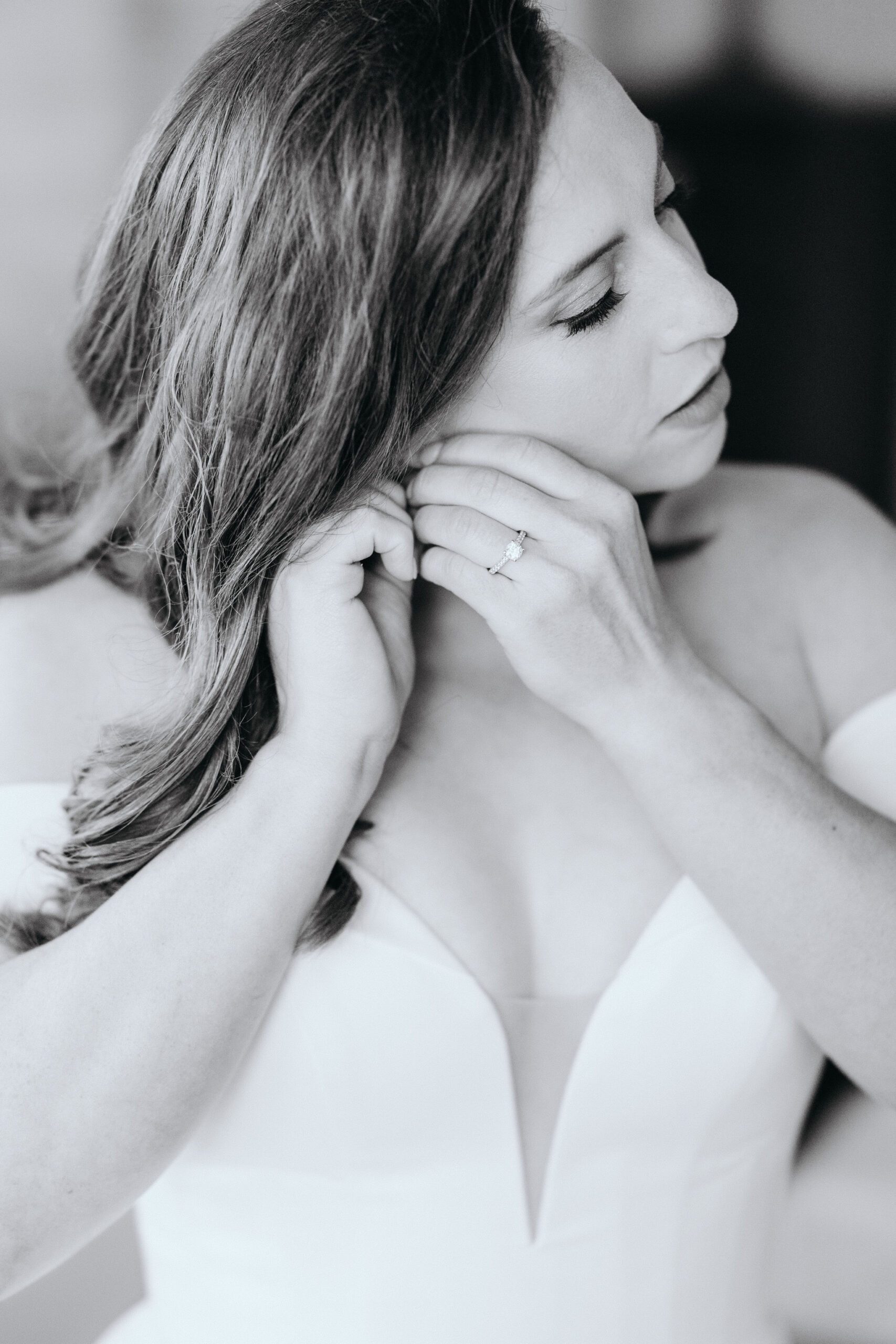 bride puts earrings on during wedding day getting ready photos