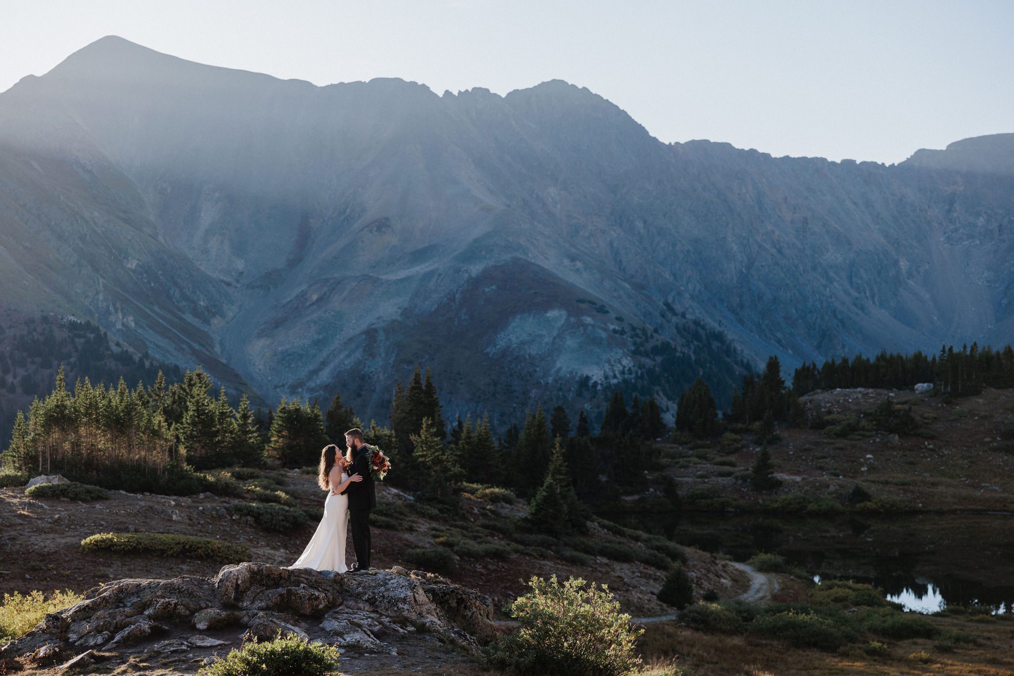 Bride and groomstand on rock overlooking the mountains in colorado during elopement