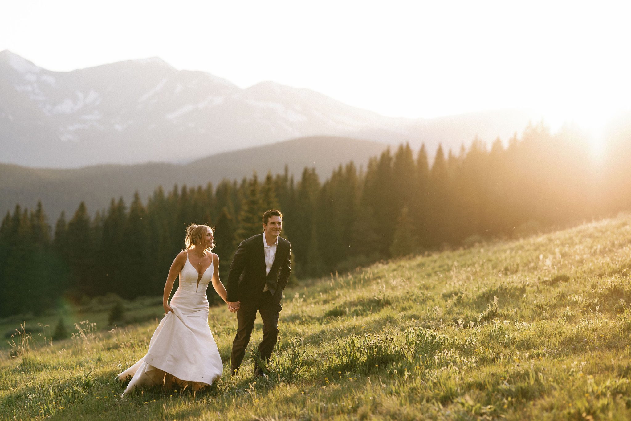bride and groom hold hands and run through mountains during dry wedding