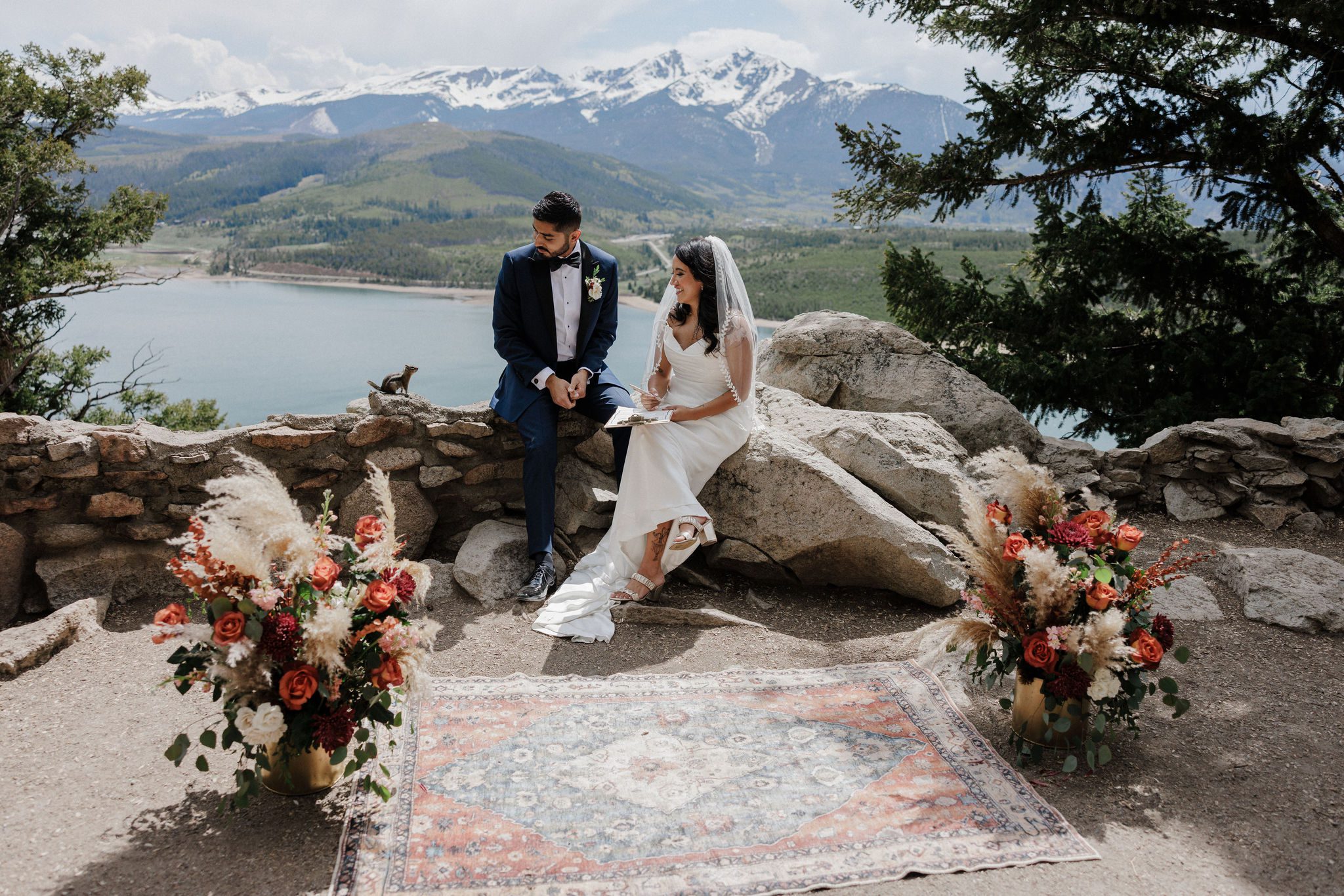 bride and groom sit on rock and look at chipmunk while signing marriage license at dry wedding