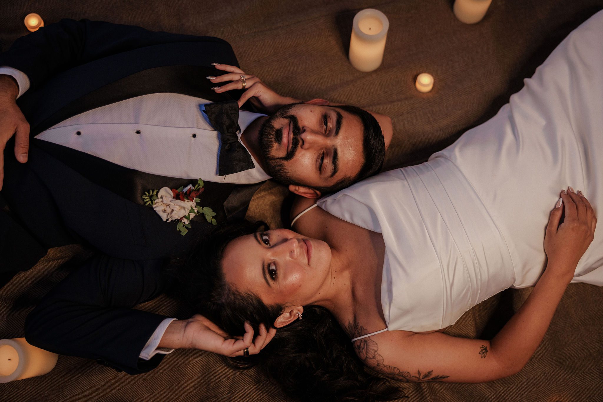 after teling family they eloped, bride and groom lay on the ground on a blanket and look at the camera