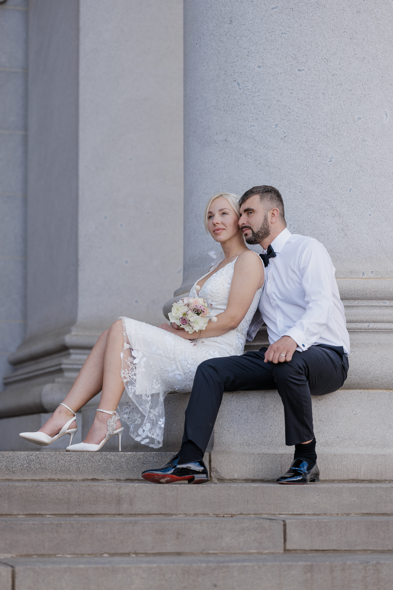 Bride and groom sit on Denver courthouse steps during elegant downtown elopement.