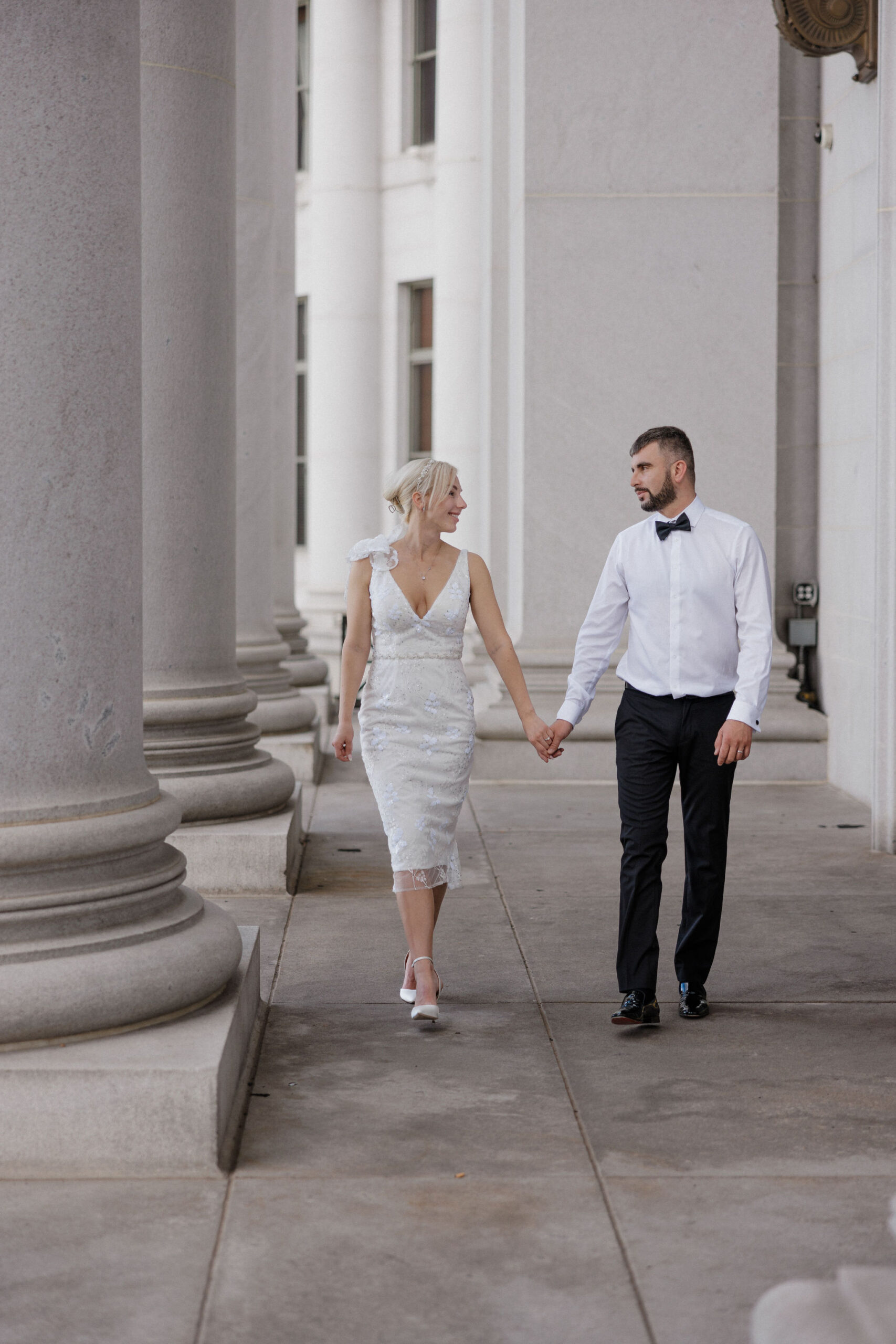 bride and groom walk down columns of denver courthouse during elopement