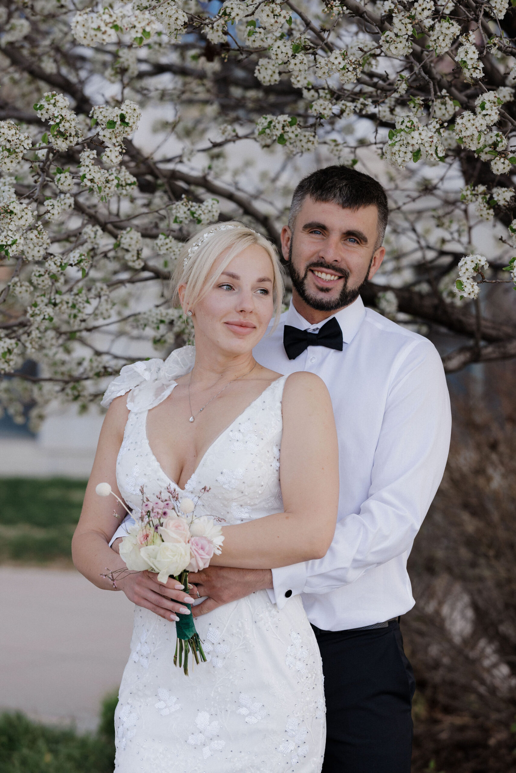 bride and groom stand in front of cherry blossom tree during denver courthouse elopement