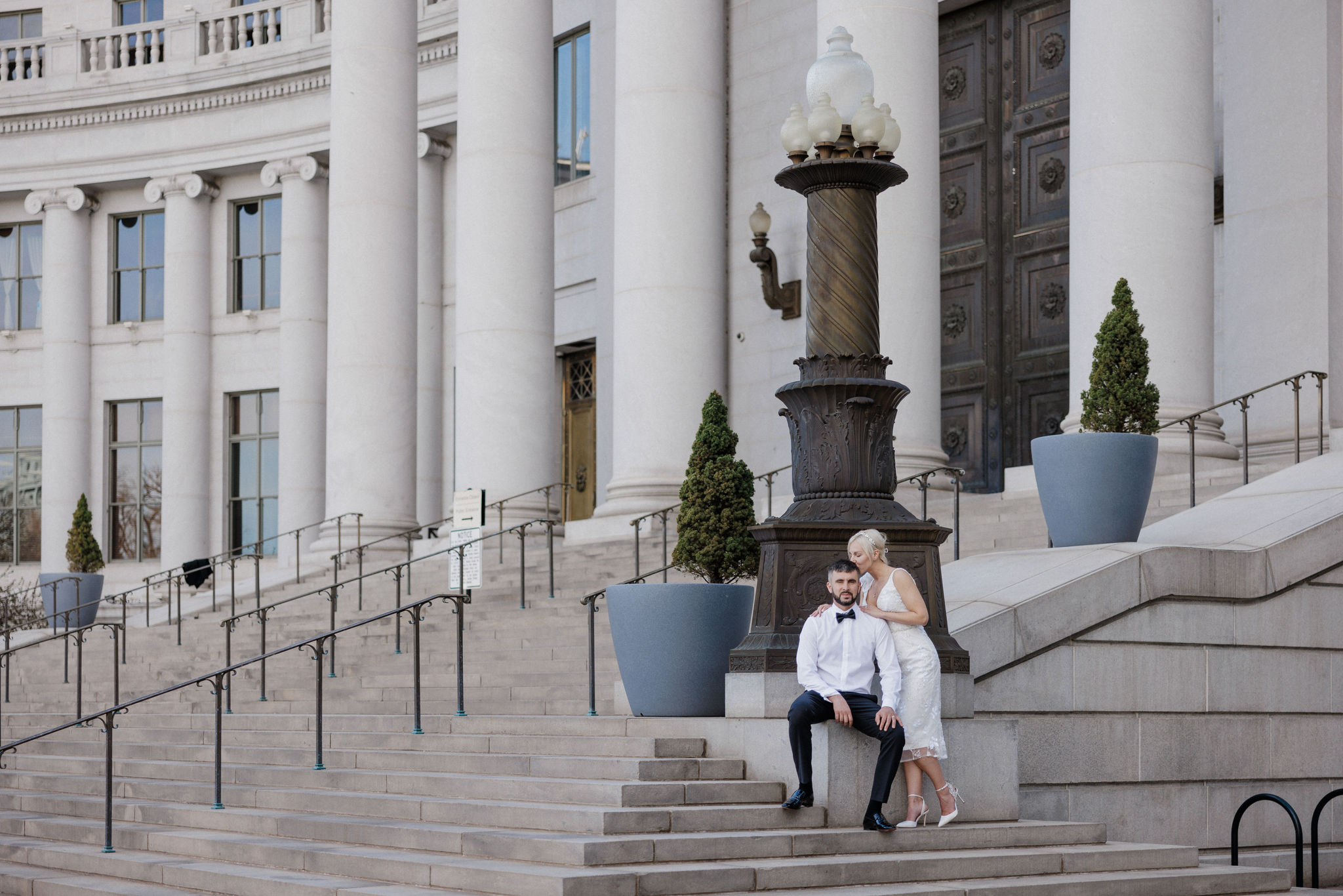 bride and groom sit on steps of denver courthouse during elopement.