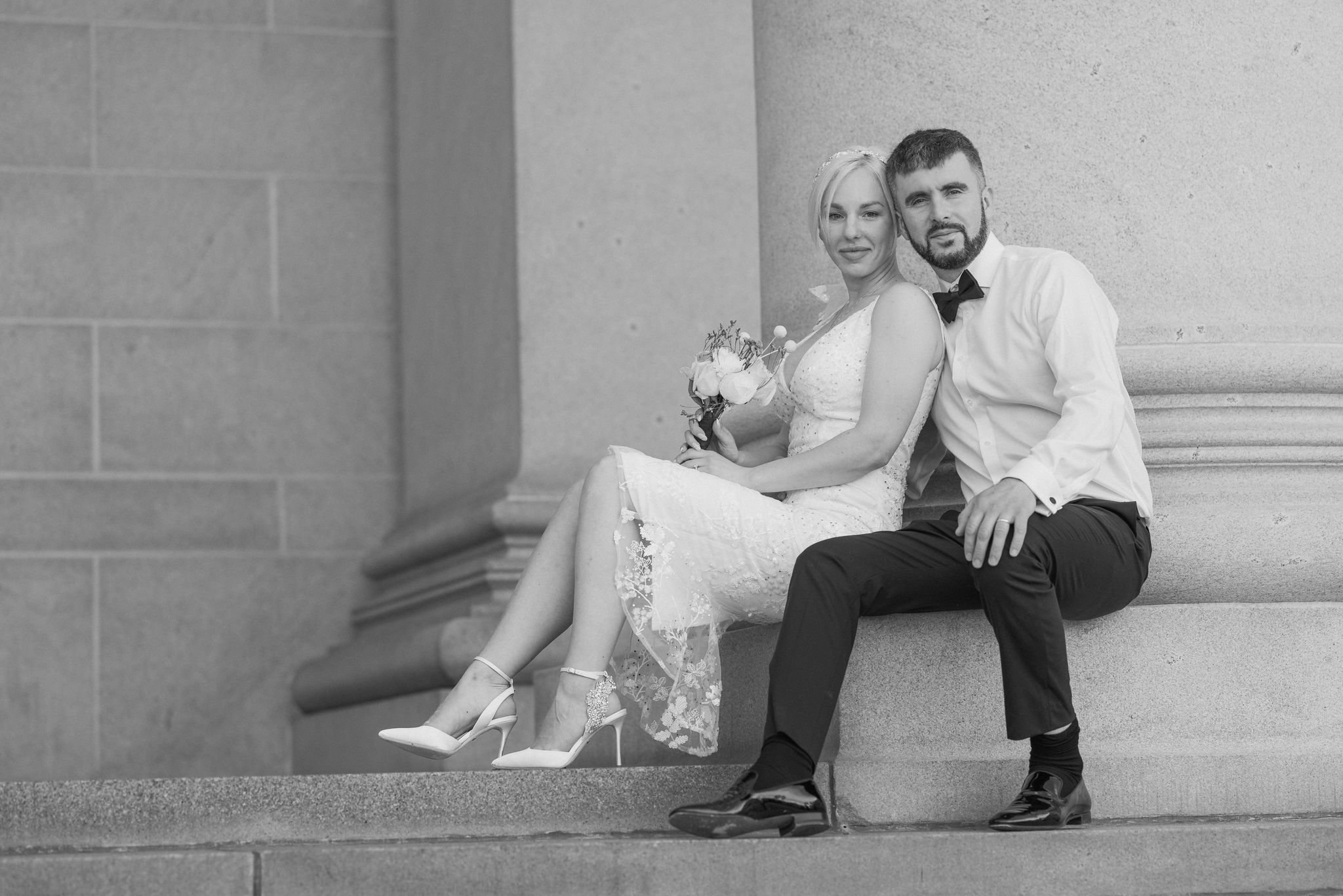 bride and groom sits on steps of denver courthouse during elopement day.