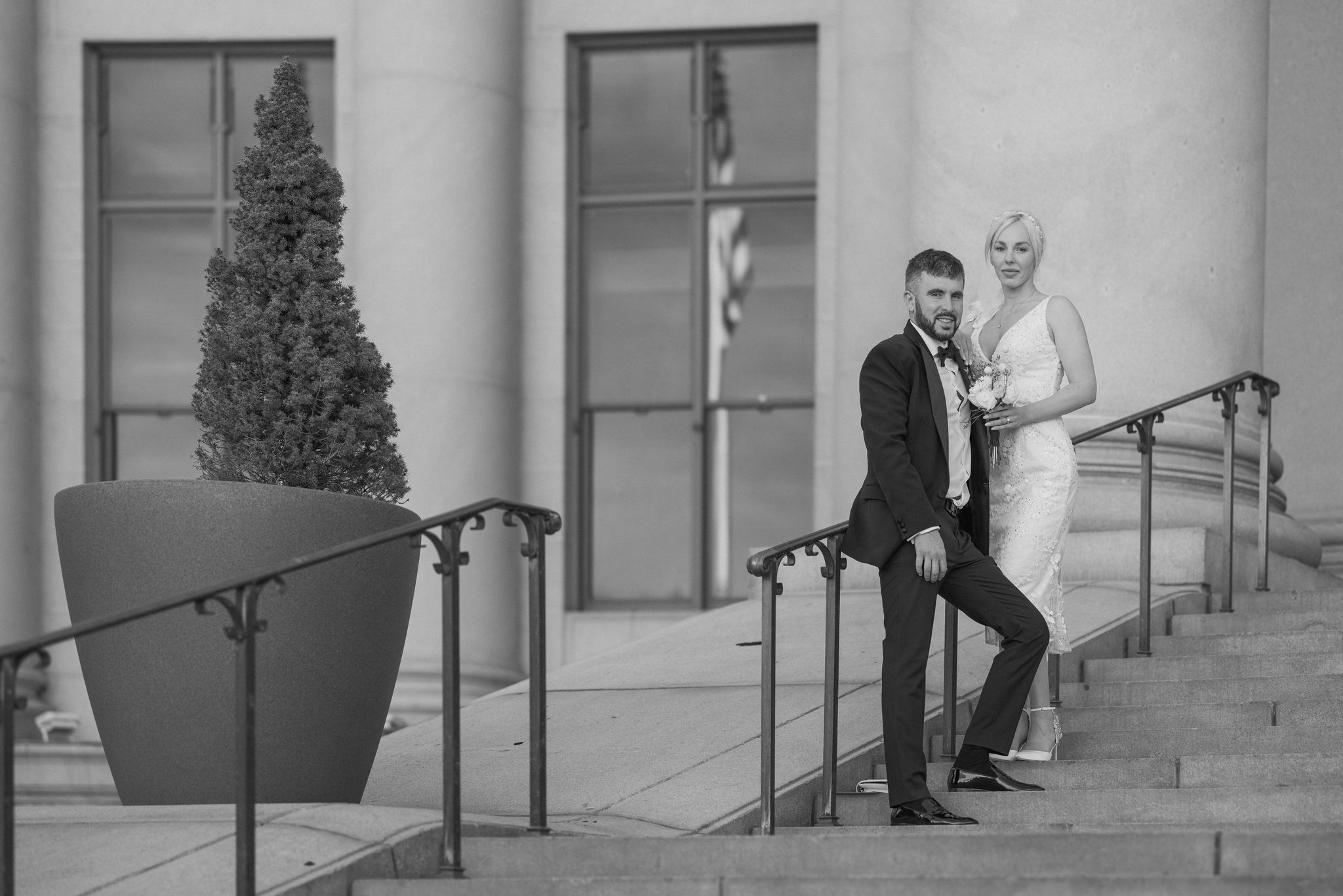 bride and groom lean on railing during denver courthouse elopement.