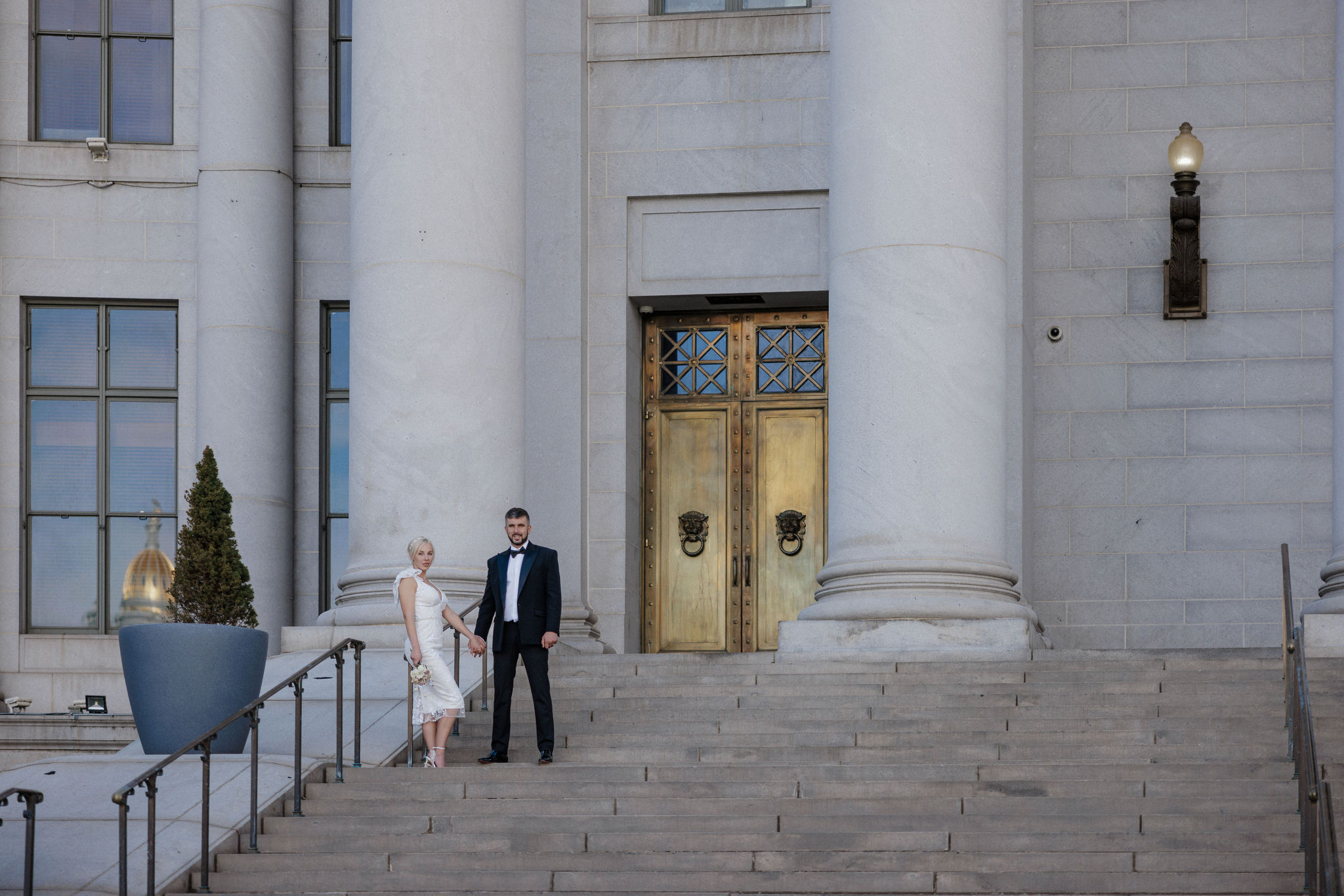 bride and groom stand on courthouse steps during denver elopement.