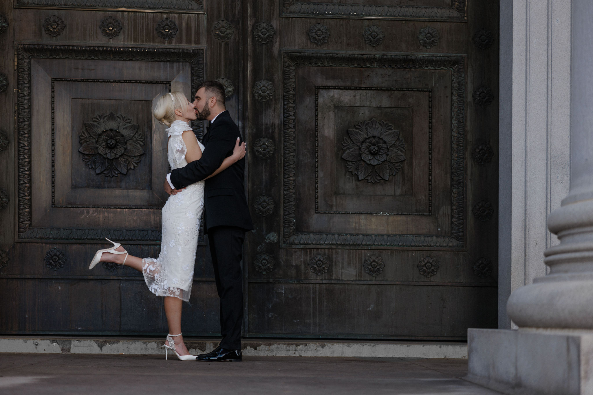bride and groom kiss in front of denver courthouse during colorado elopement.