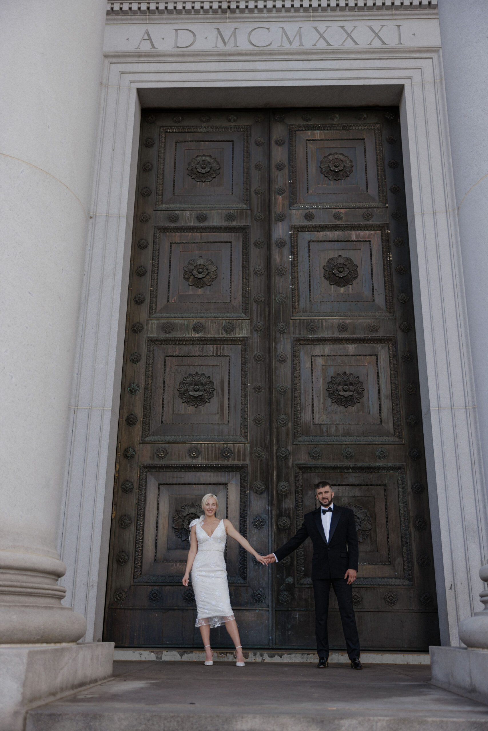 bride and groom stand in front of door at denver district court during elopement.