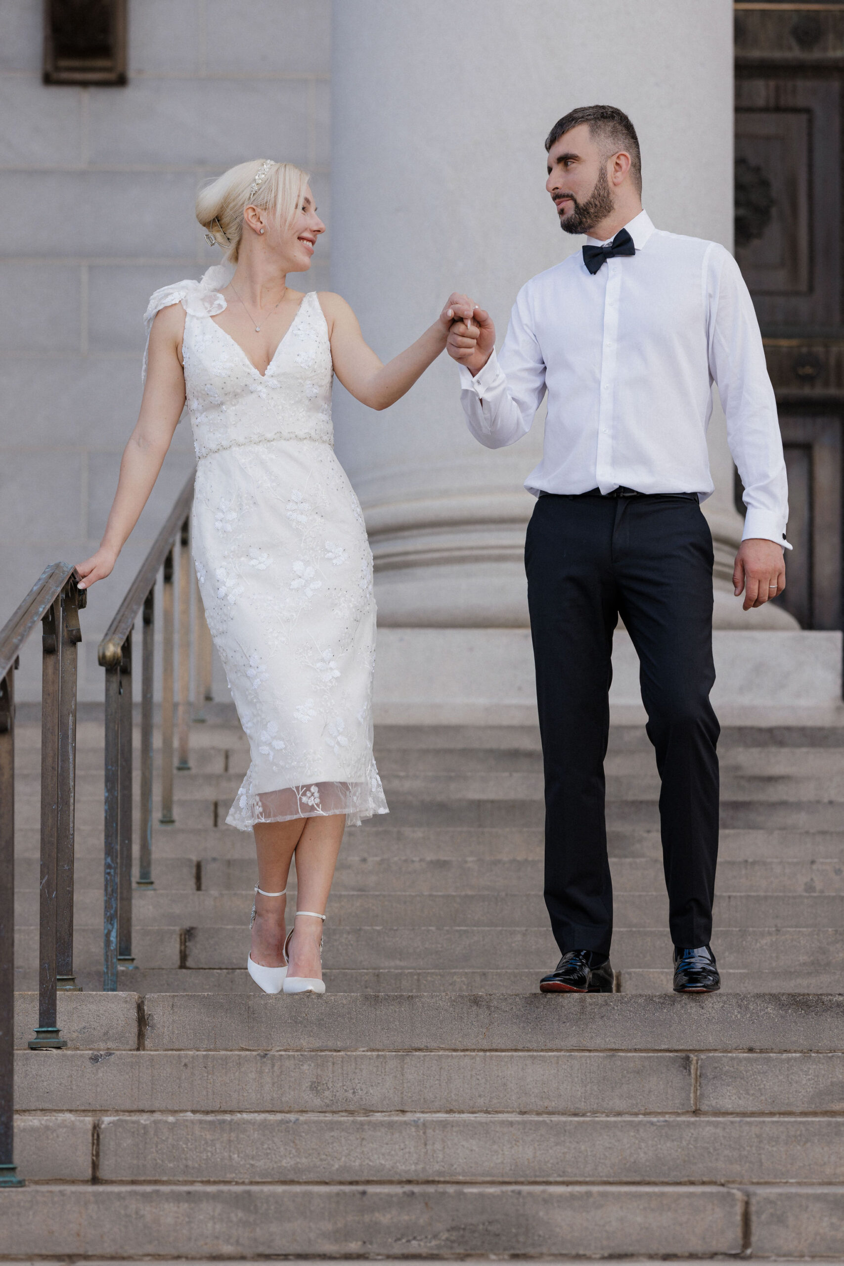 bride and groom walk down steps hand in hand at denver courthouse during elopement day